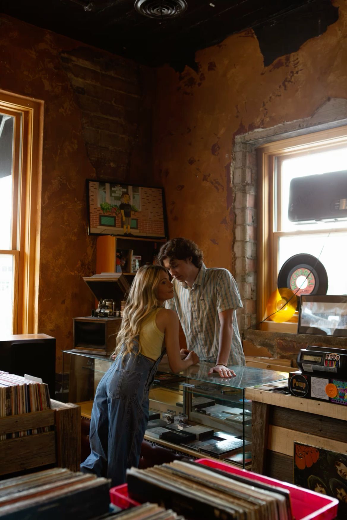 A couple browses vinyl records together in a cozy, warmly lit vintage record shop with rustic brick walls.