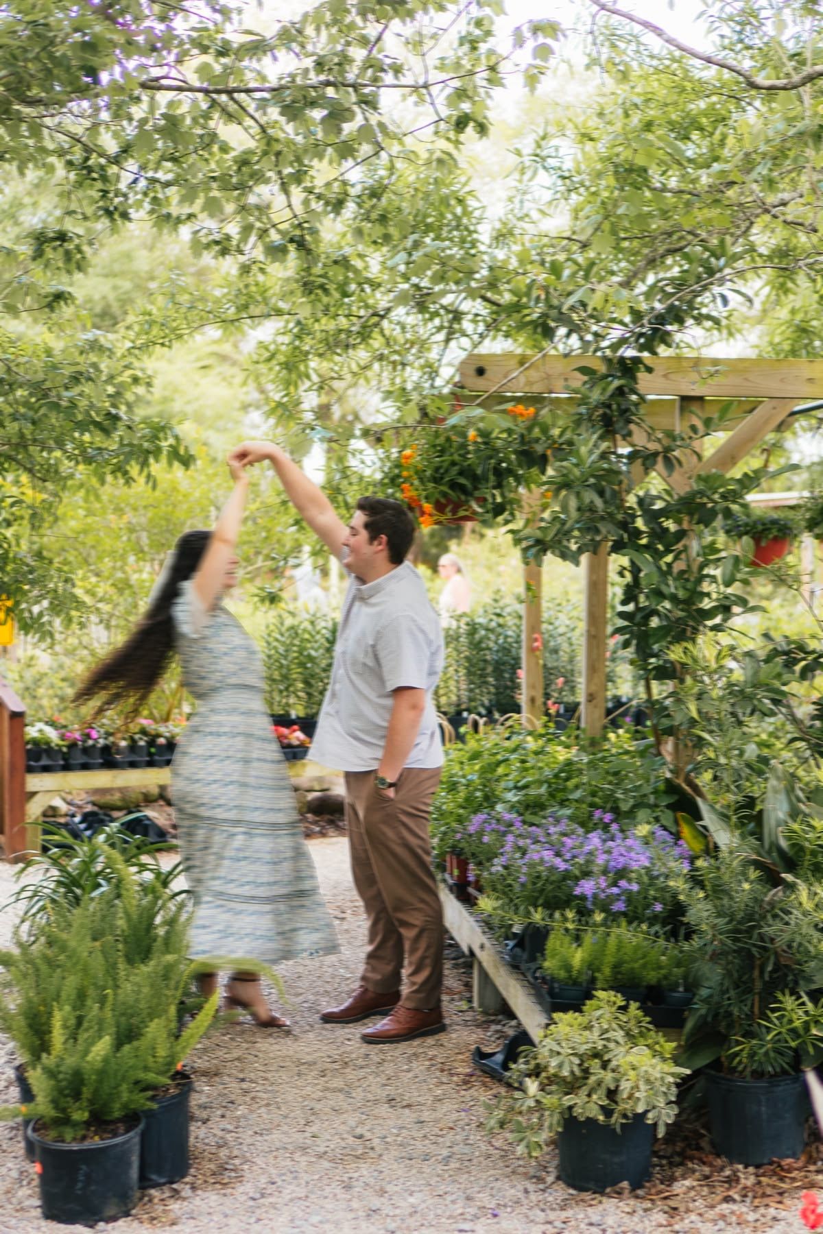 Couple dancing among lush plants and flowers at an outdoor garden nursery surrounded by greenery.