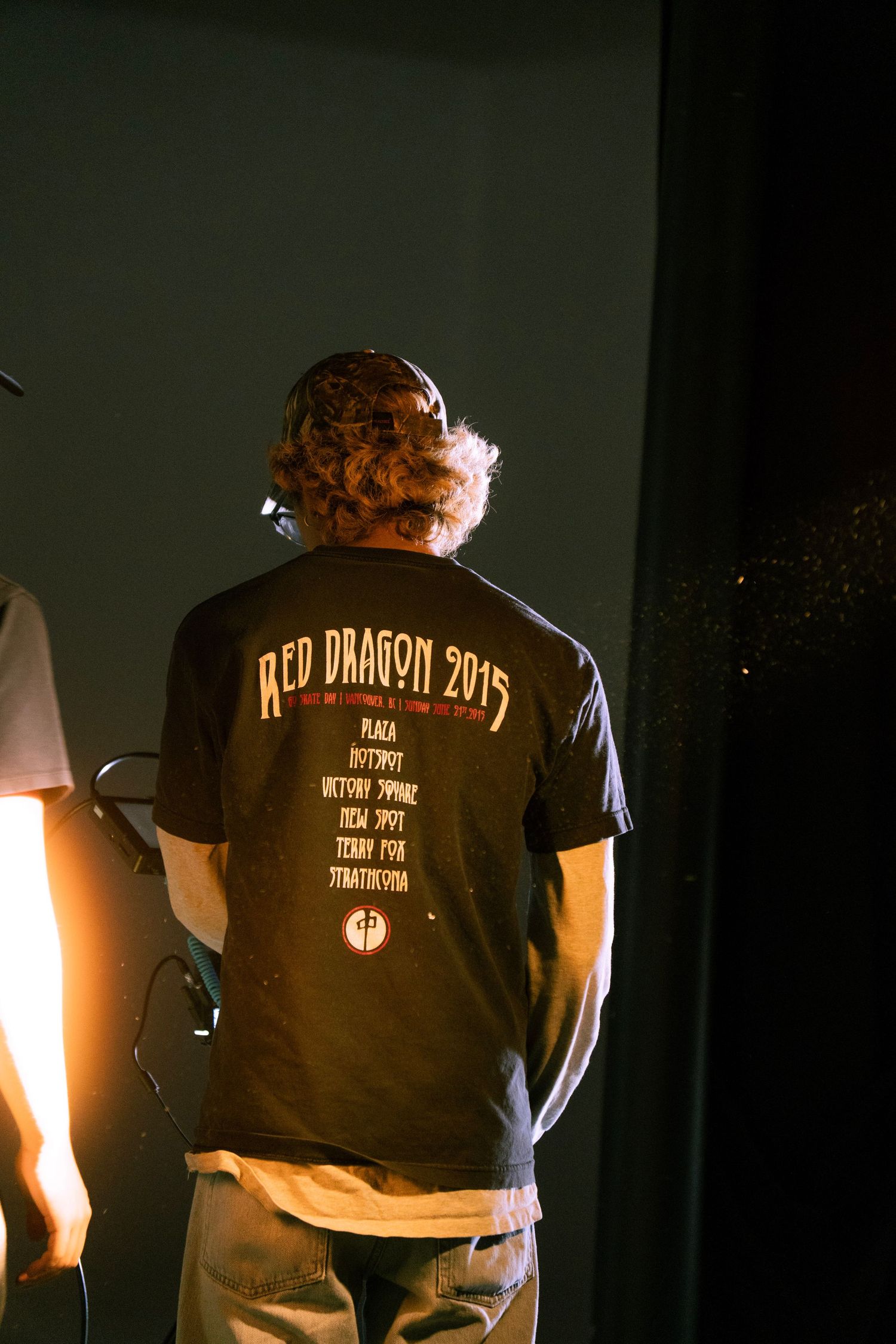 Person wearing a black Red Dragon 2015 tour t-shirt standing on a dimly lit stage.