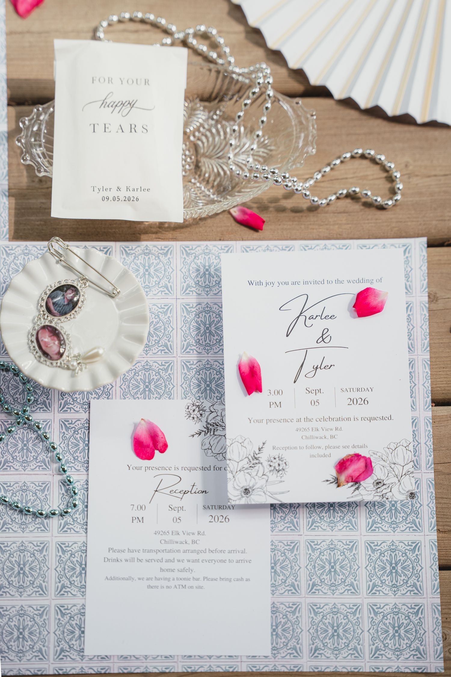 Elegant wedding invitation suite with floral accents on blue tile pattern, paired with jewelry and happy tears packet.