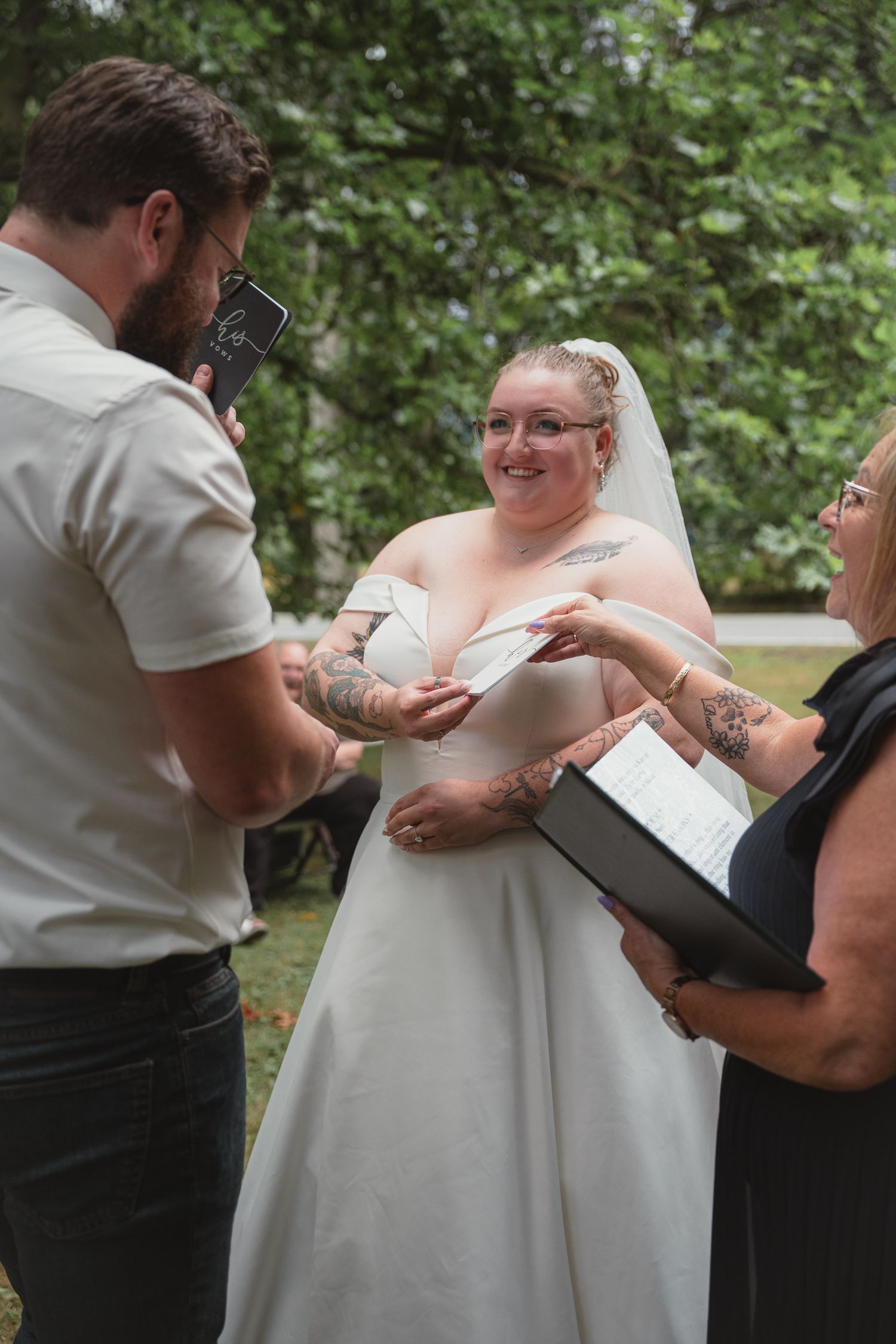 Bride in white gown exchanging vows with groom at outdoor wedding ceremony.