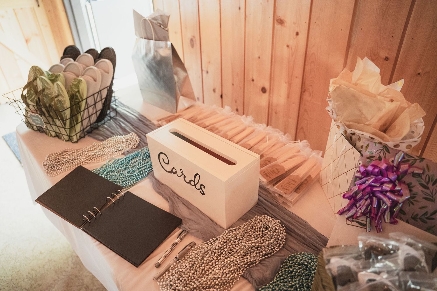 Wedding card box and guest book displayed on table with decorative beads and paper fans.