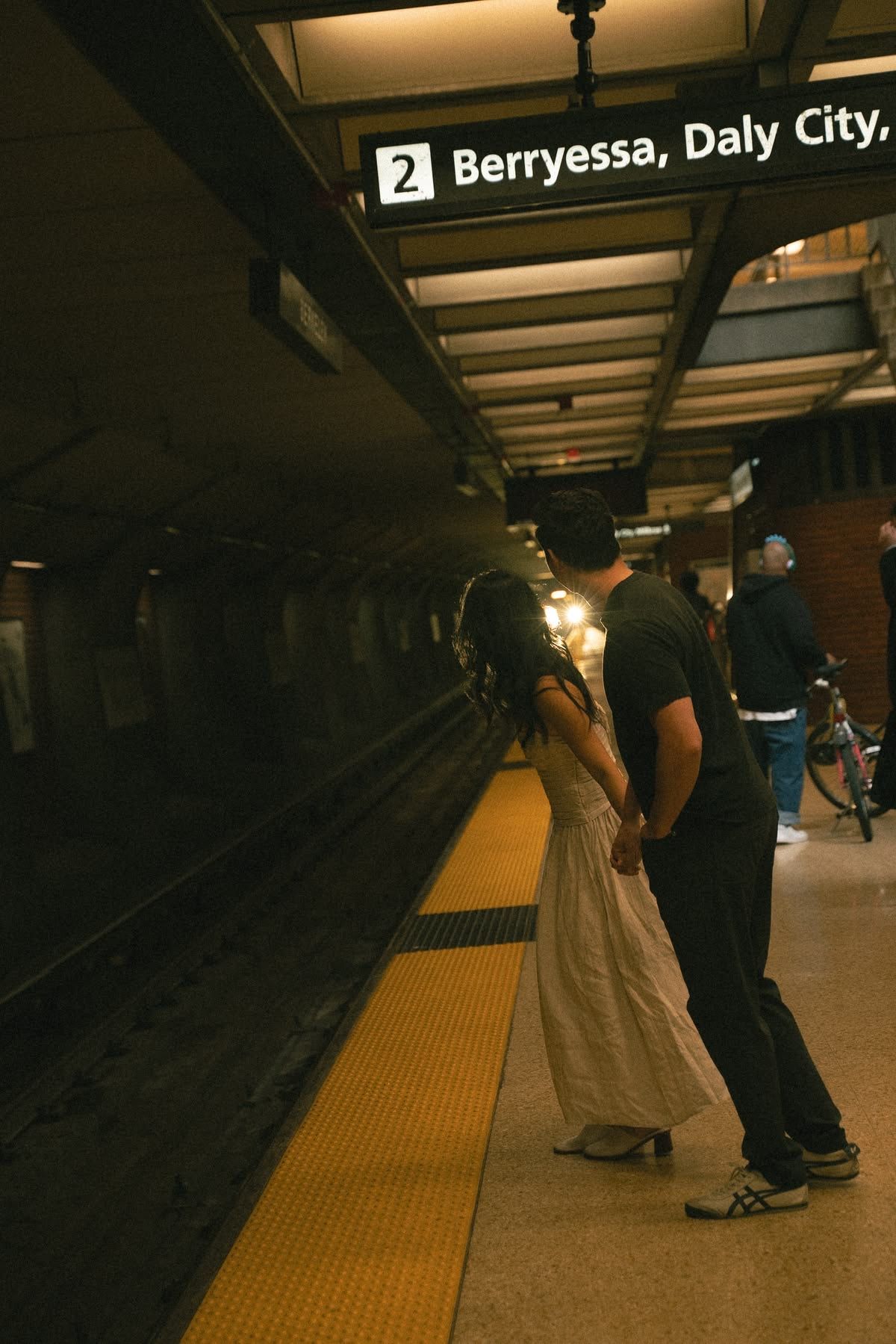 Couple holding hands on a BART subway platform at Berryessa Daly City station, waiting for the train.
