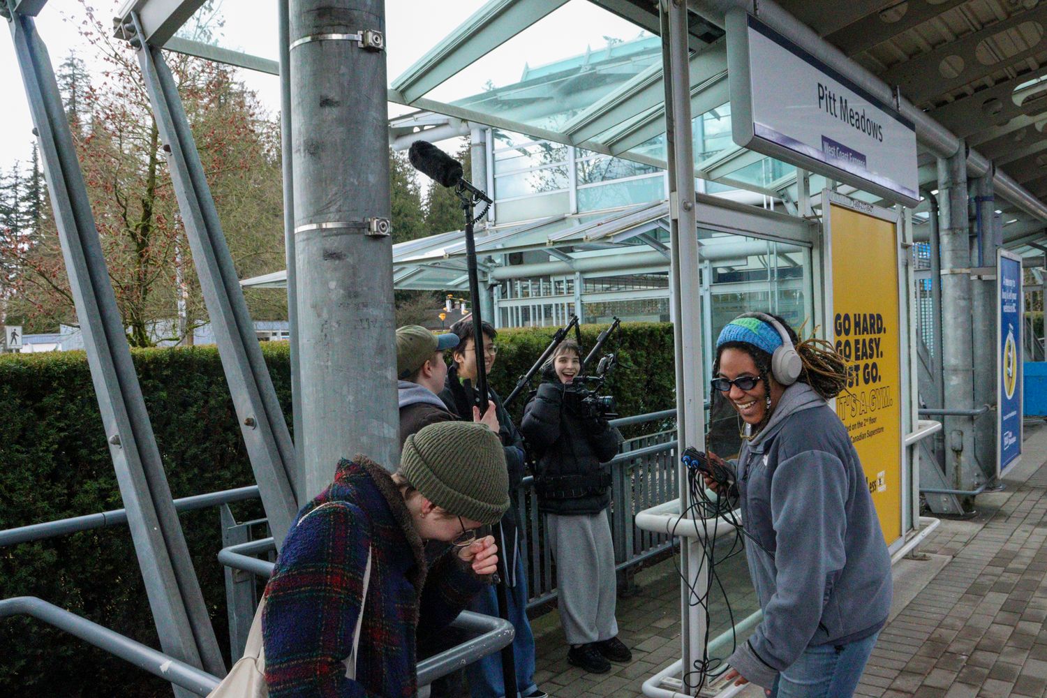 Film crew recording at Pitt Meadows transit station with boom microphone.