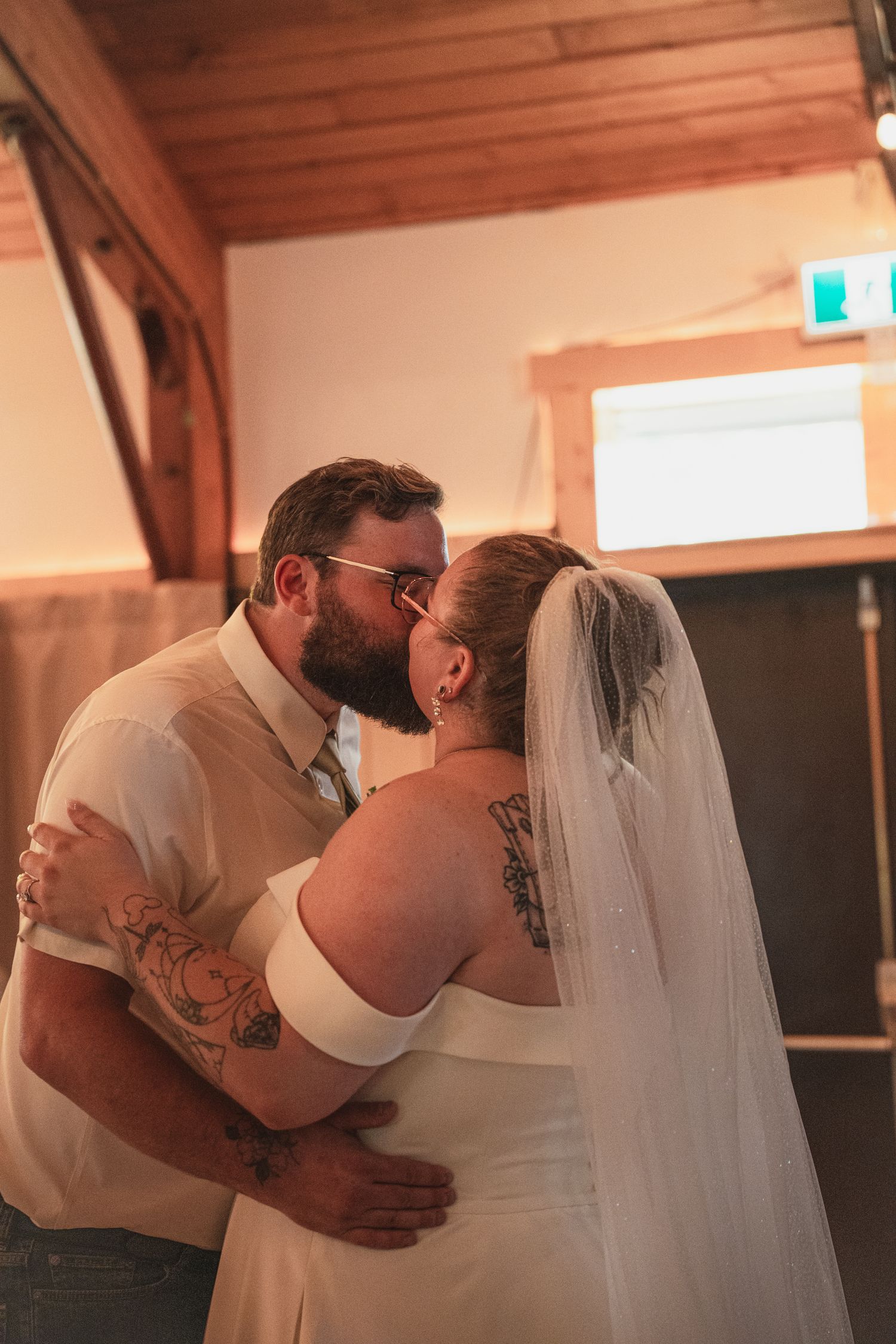 Bride and groom sharing a romantic kiss during first dance at rustic barn wedding reception.
