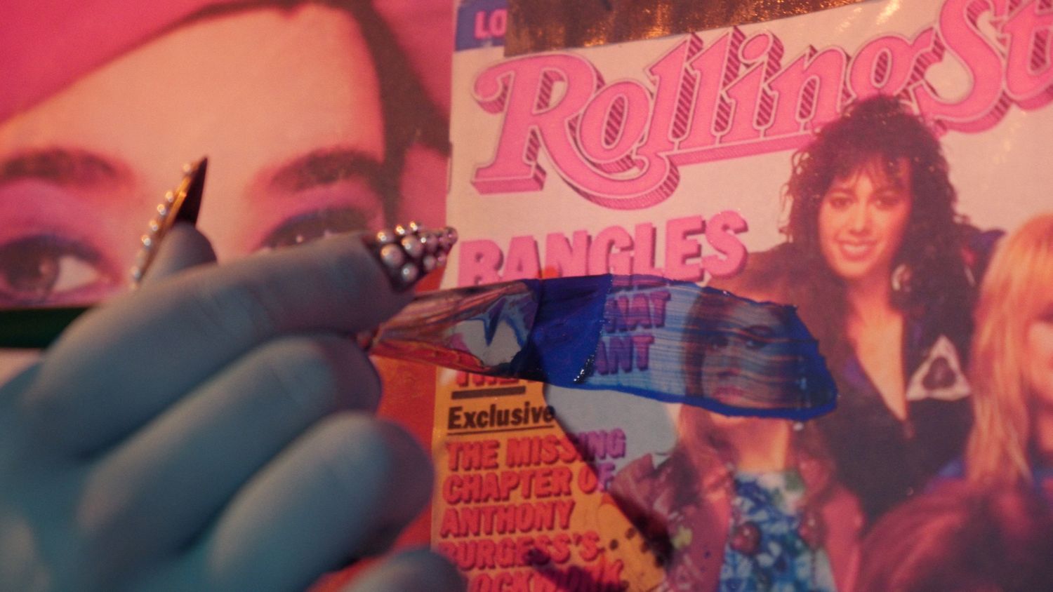 Gloved hand holding a pen over a vintage Rolling Stone magazine featuring bangles cover story.