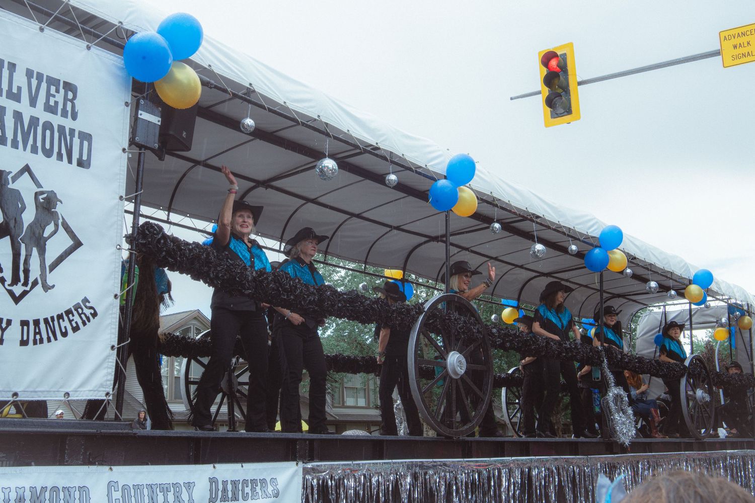 Silver Diamond Country Dancers performing on decorated float with blue and yellow balloons.