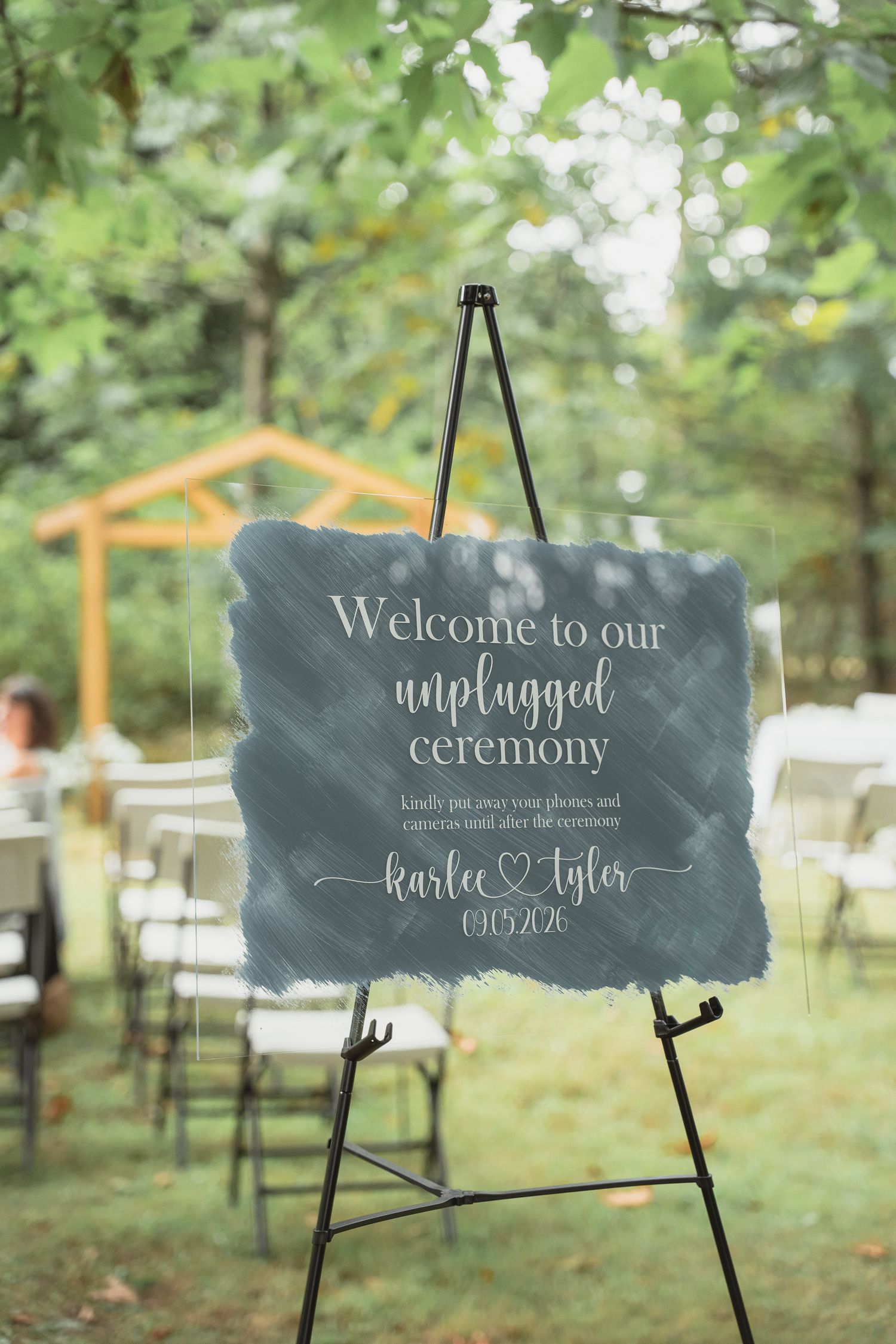 Outdoor wedding unplugged ceremony sign on easel reading Welcome to our unplugged ceremony Karlee and Tyler 09.05.20.