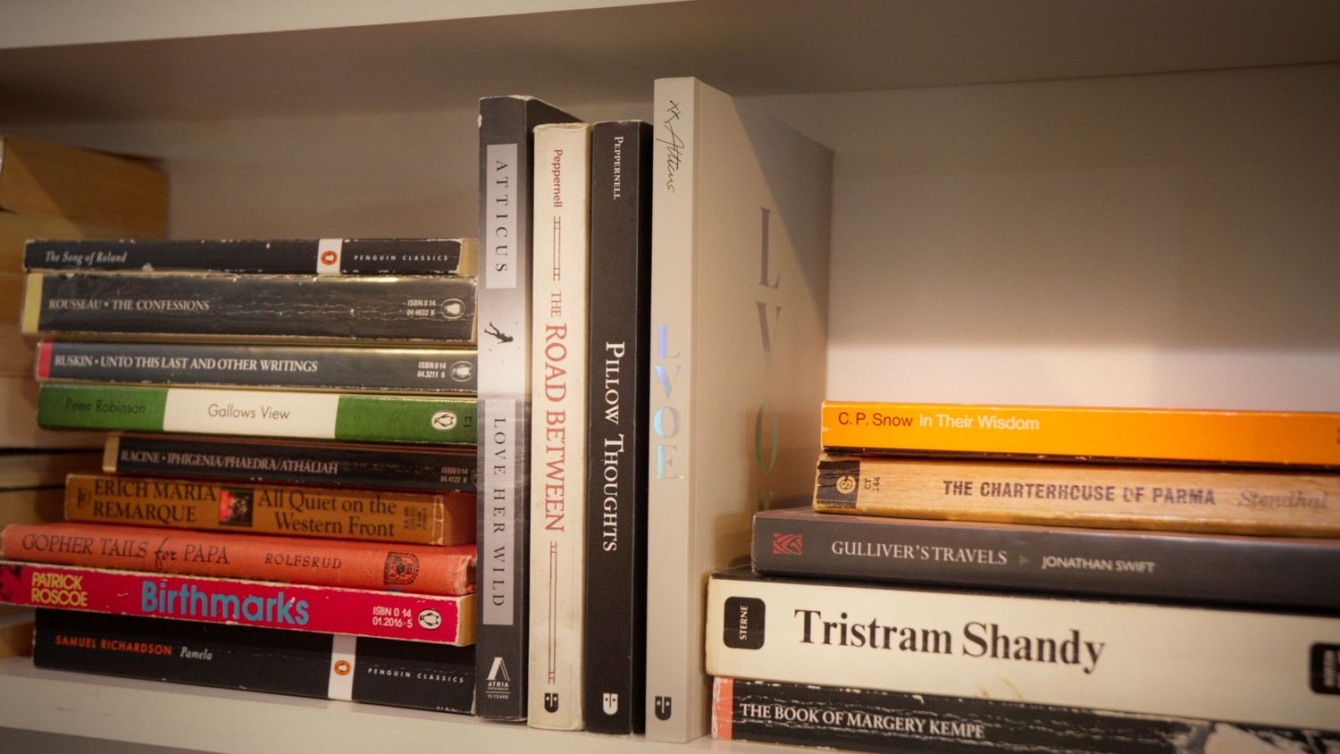 Close-up of colorful books on a white shelf including Tristram Shandy and Peter Ackroyd titles.
