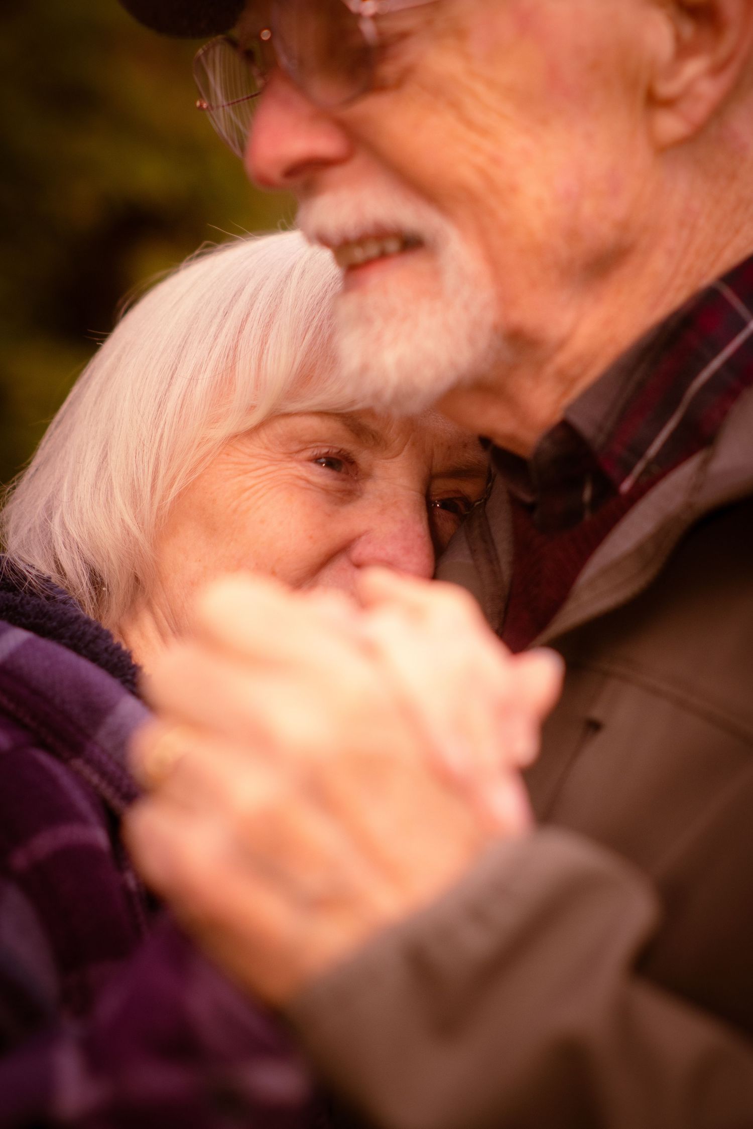 Close-up of elderly couple slow dancing, woman resting head near man's cheek tenderly.