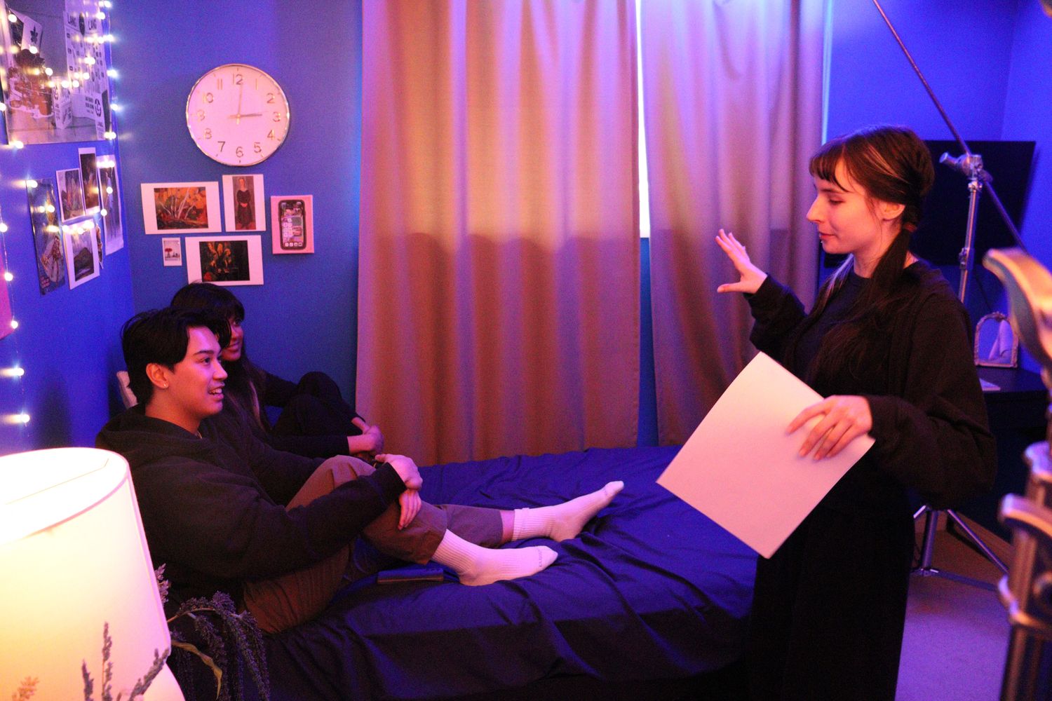 Director giving instructions to an actor lying on a bed during an indoor film shoot.