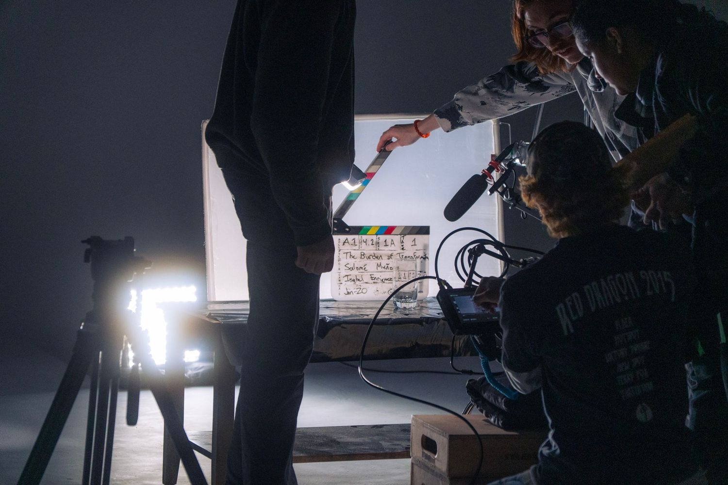Film crew on a dark set using a clapperboard and boom mic during a professional video shoot.