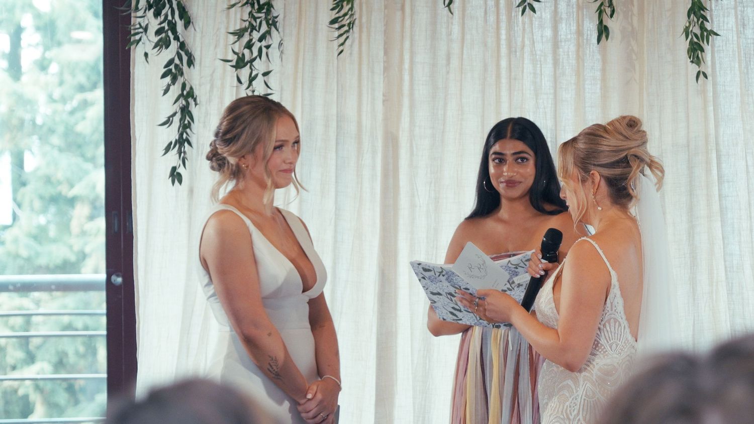 Two brides stand at the altar as an officiant reads vows during an elegant wedding ceremony.