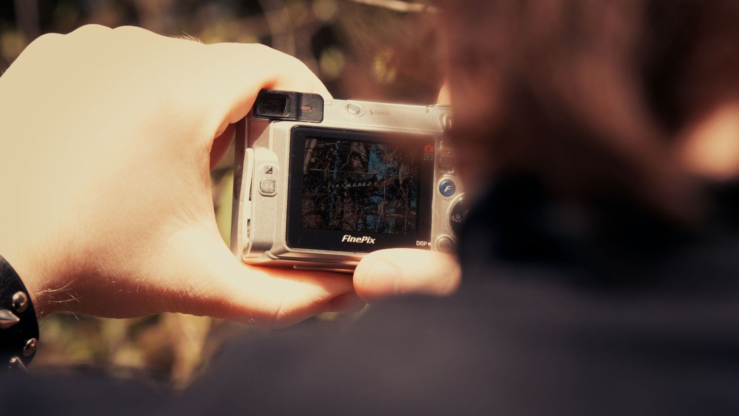 Person holding a GoPro action camera outdoors capturing nature footage.