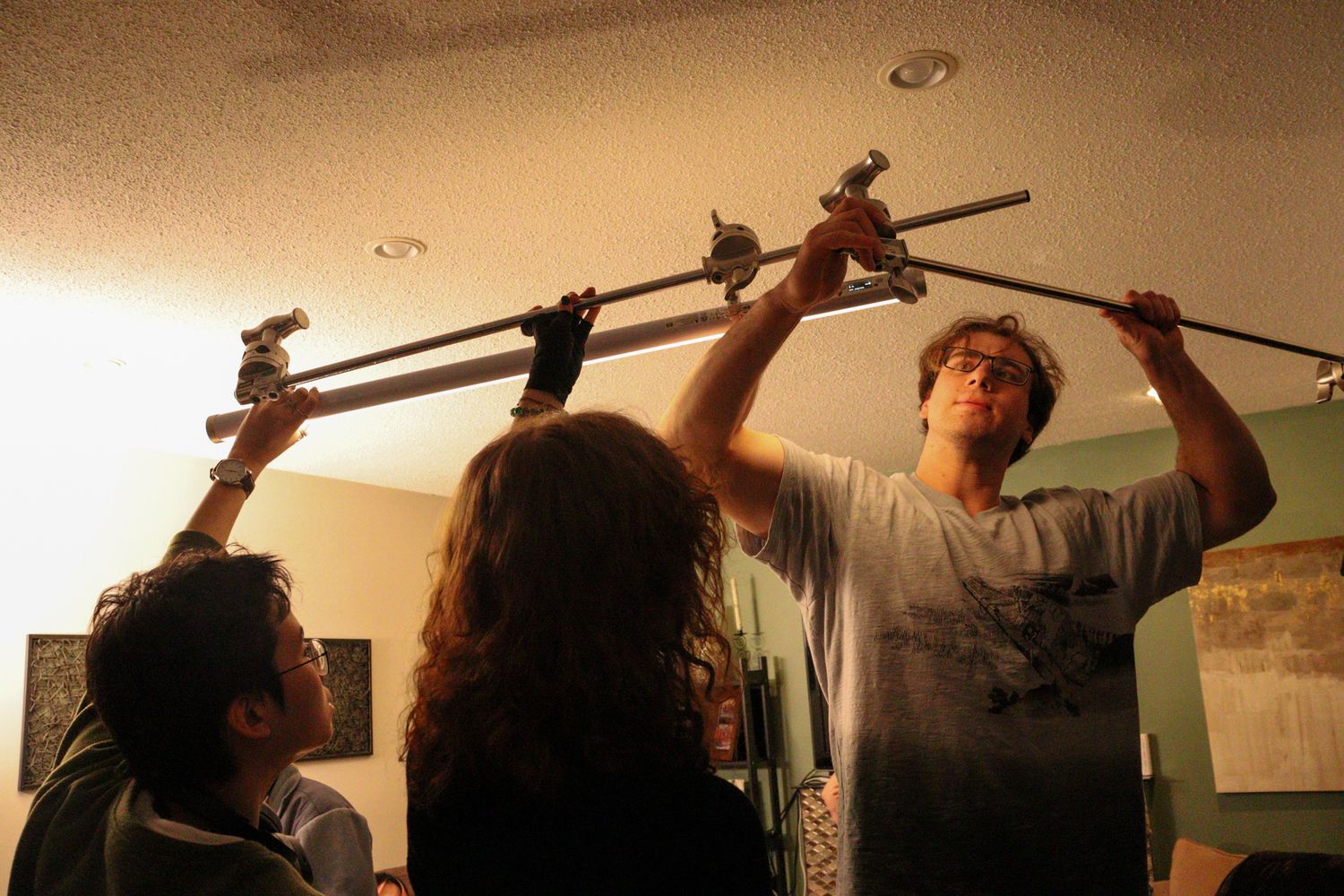 Film crew adjusts overhead camera rig equipment during indoor production shoot.