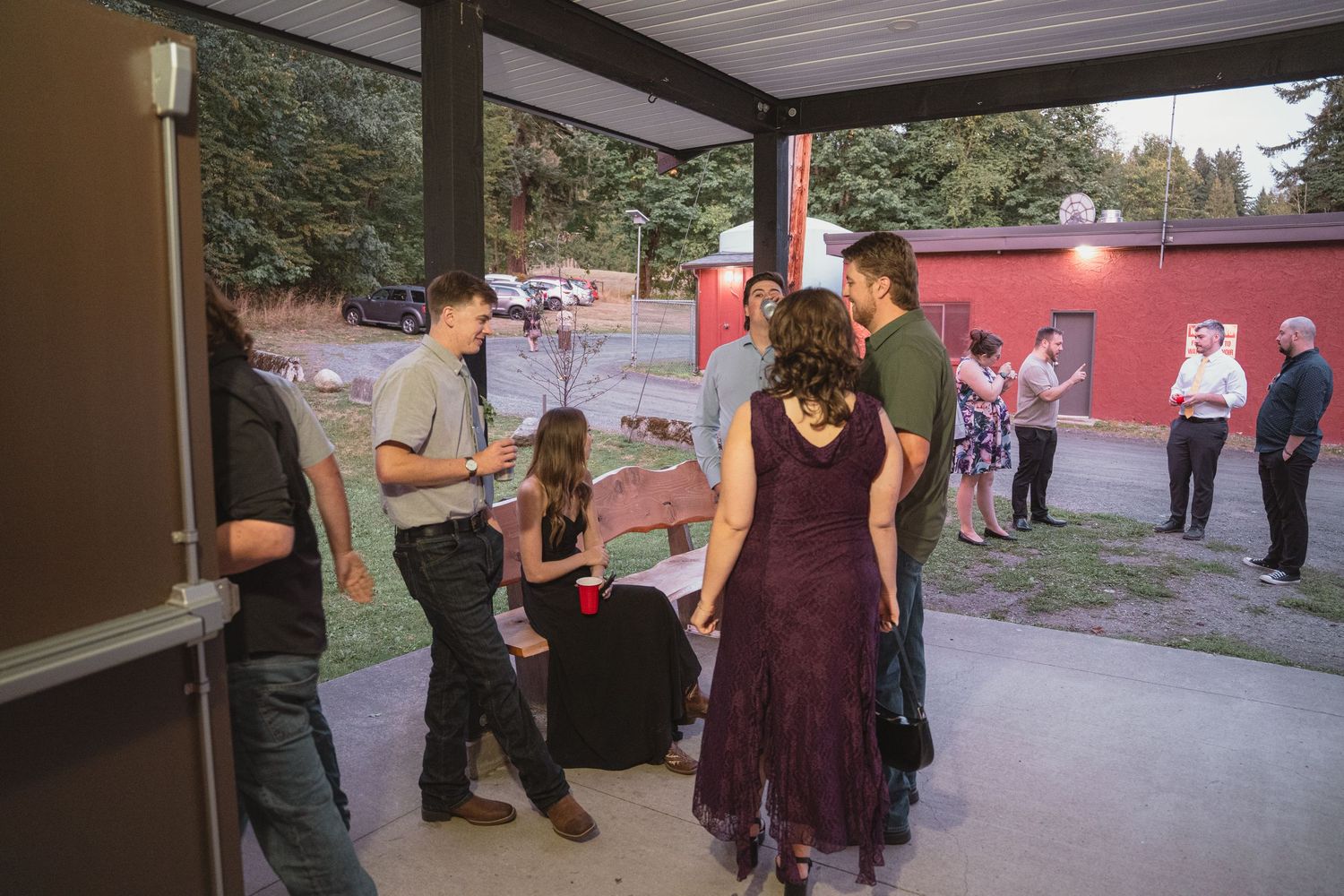 Group of people socializing on a covered outdoor patio at dusk during a casual evening gathering or party.