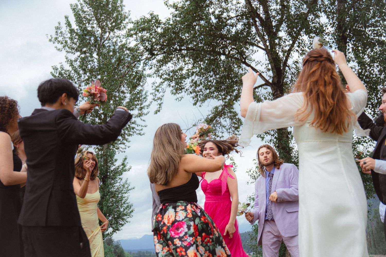 Bride and wedding guests dance joyfully together at an outdoor mountain wedding.