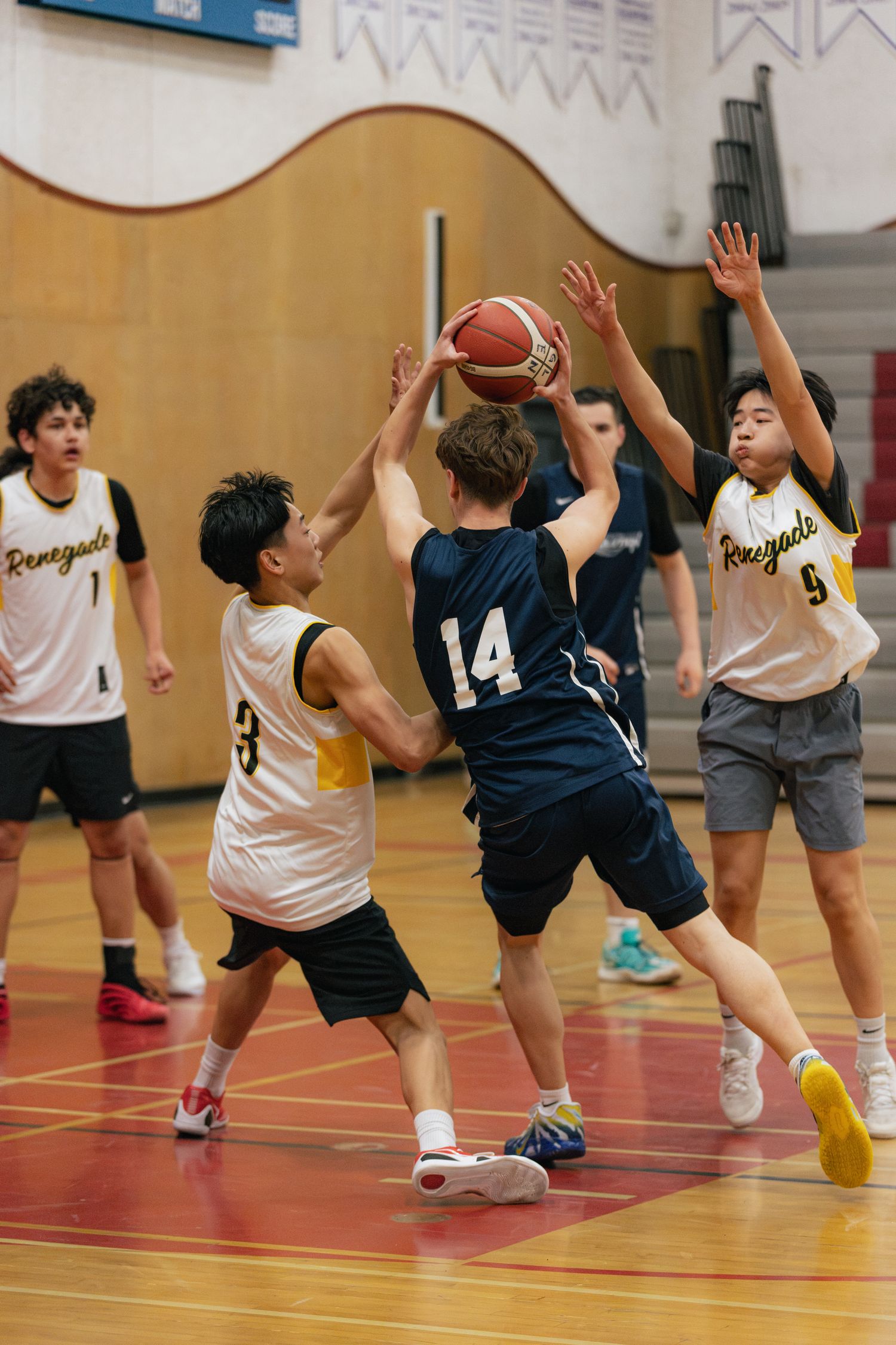 Youth basketball player in blue jersey number 14 attempts a shot while defended by Renegades players.