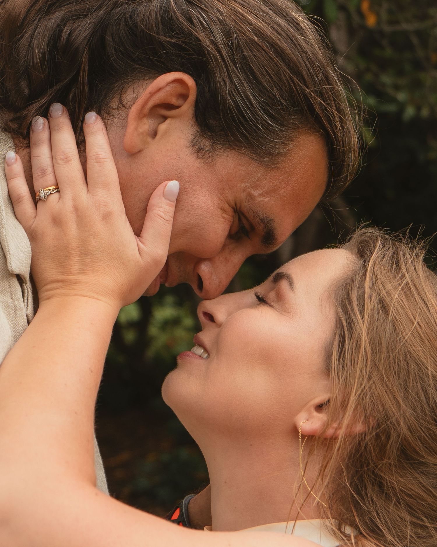 Close-up of smiling bride and groom sharing a tender nose-to-nose moment outdoors on their wedding day.