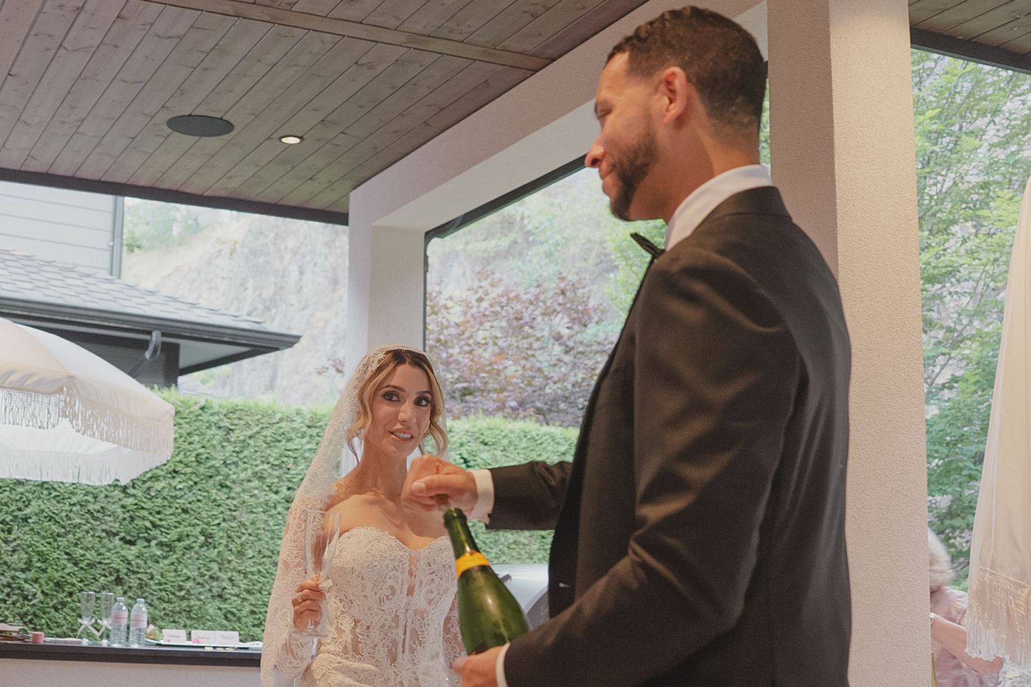 Bride and groom opening a champagne bottle together at their elegant indoor wedding reception.
