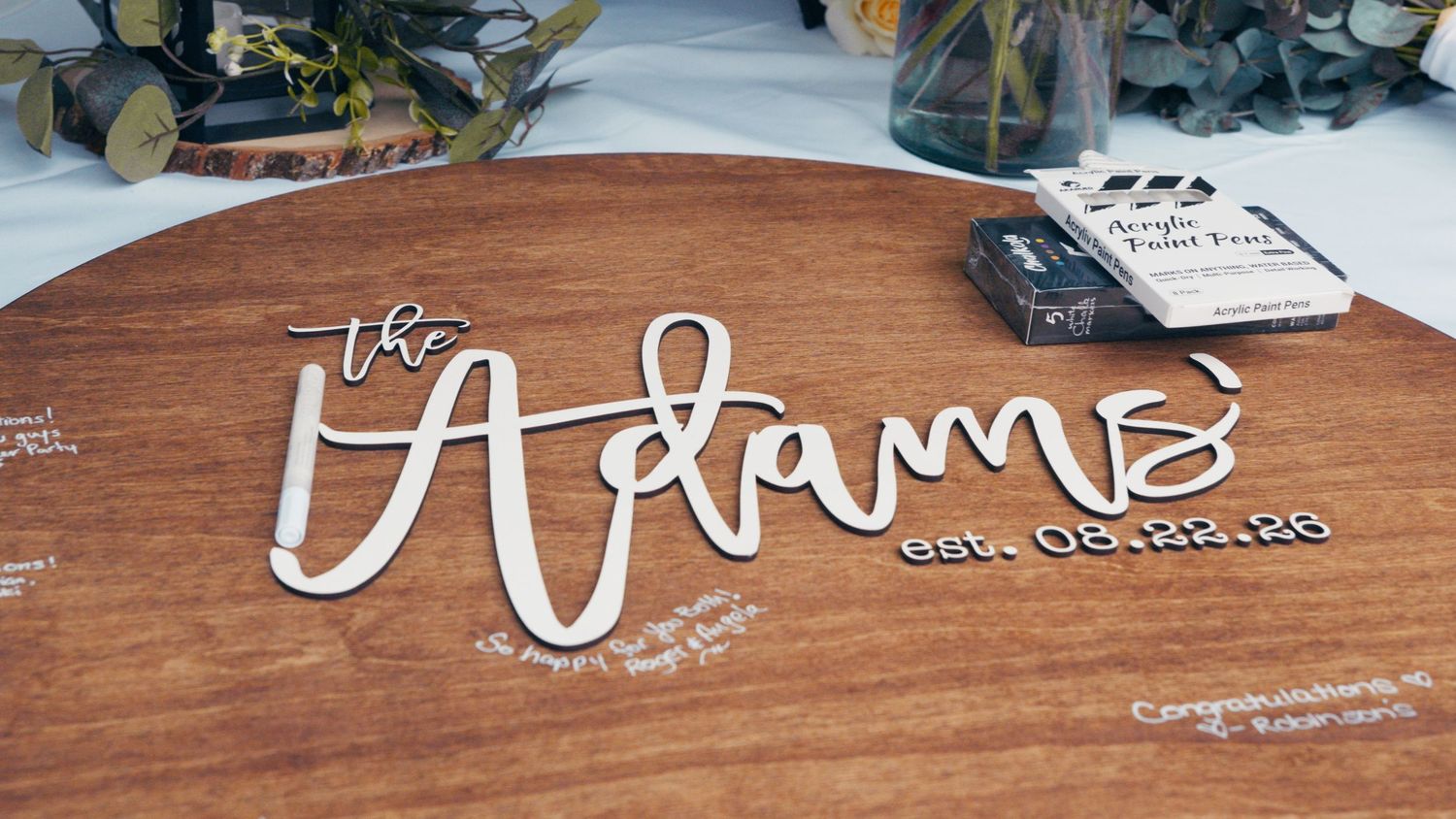 Personalized wooden wedding guest book sign reading The Adams est. 08.22.23 on a round wood platter.