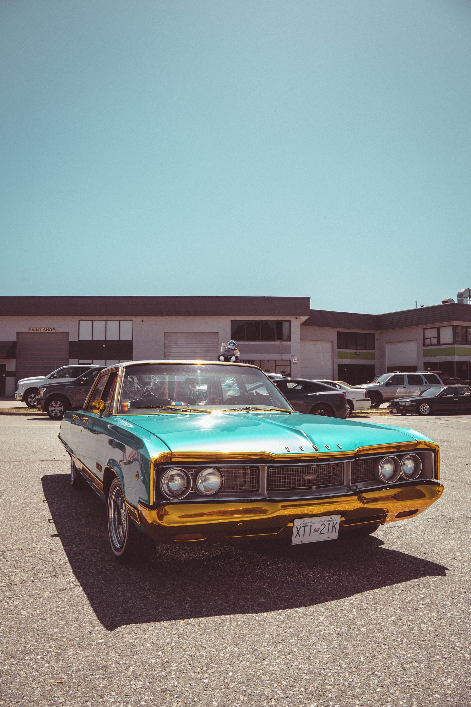 Stunning teal and gold vintage Dodge classic car parked in a sunny lot at an outdoor car show.