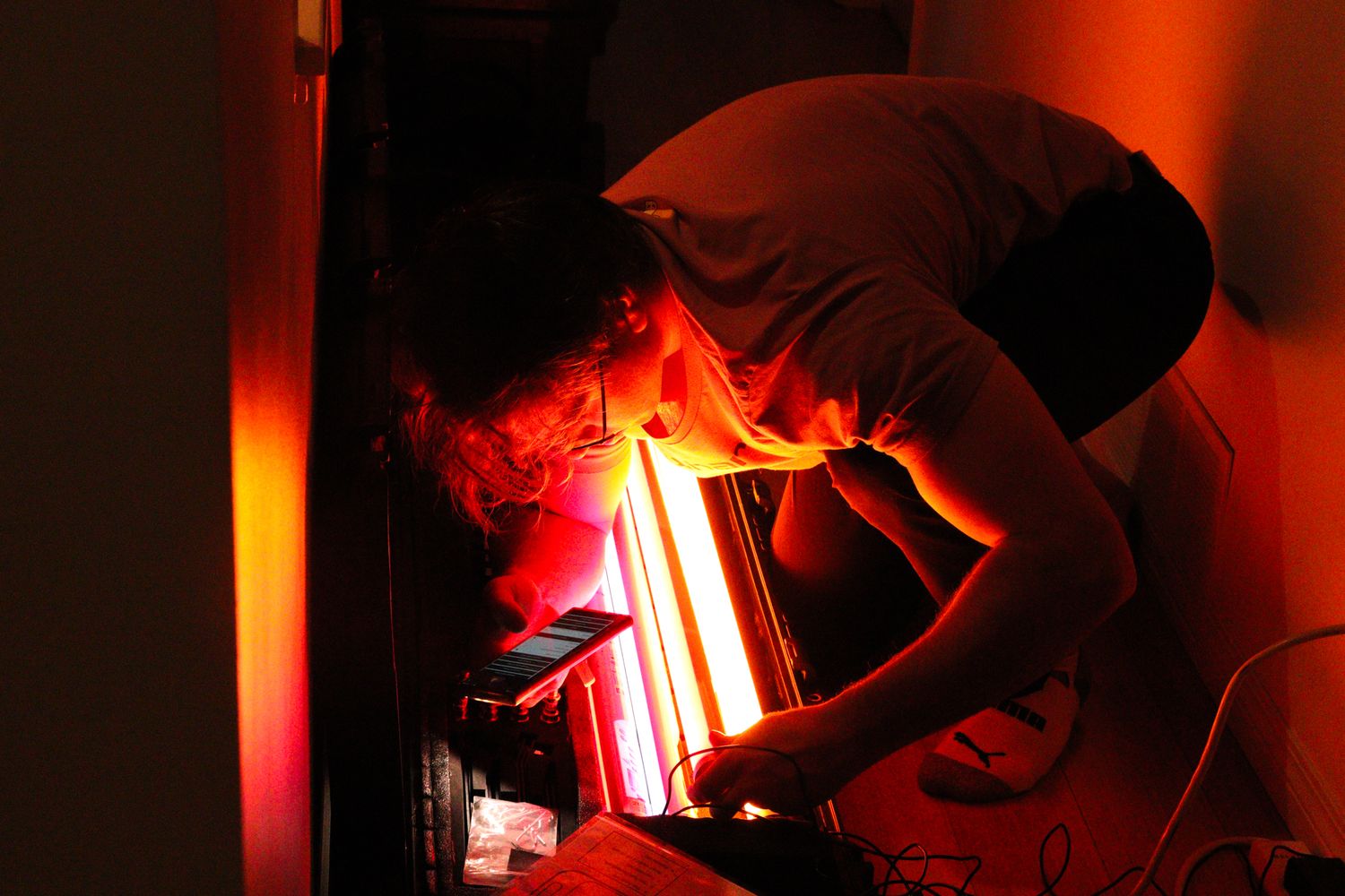 Person working with glowing red studio lights in a dark room during a film production.