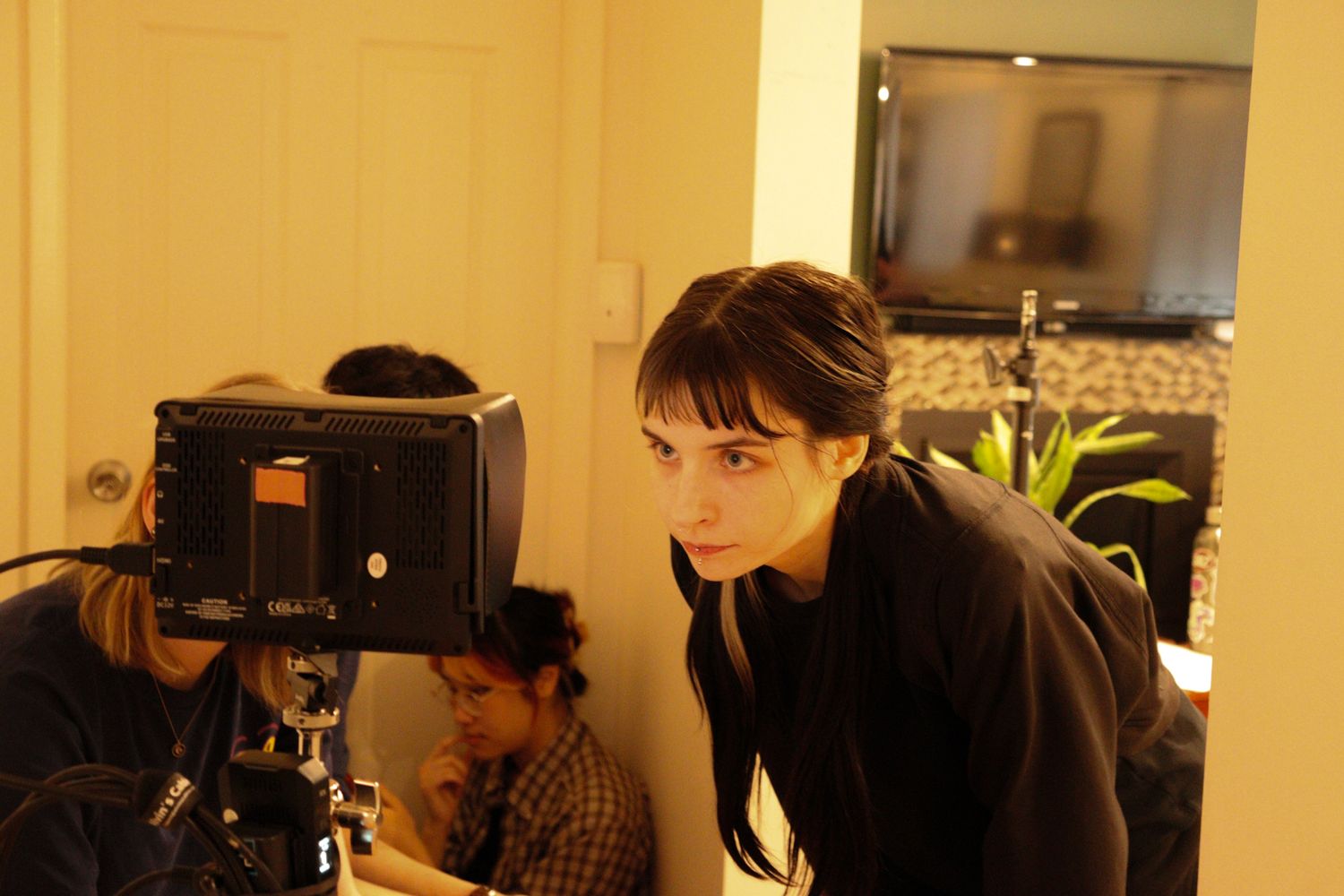 Young female director leans over a professional film camera during an indoor production shoot.
