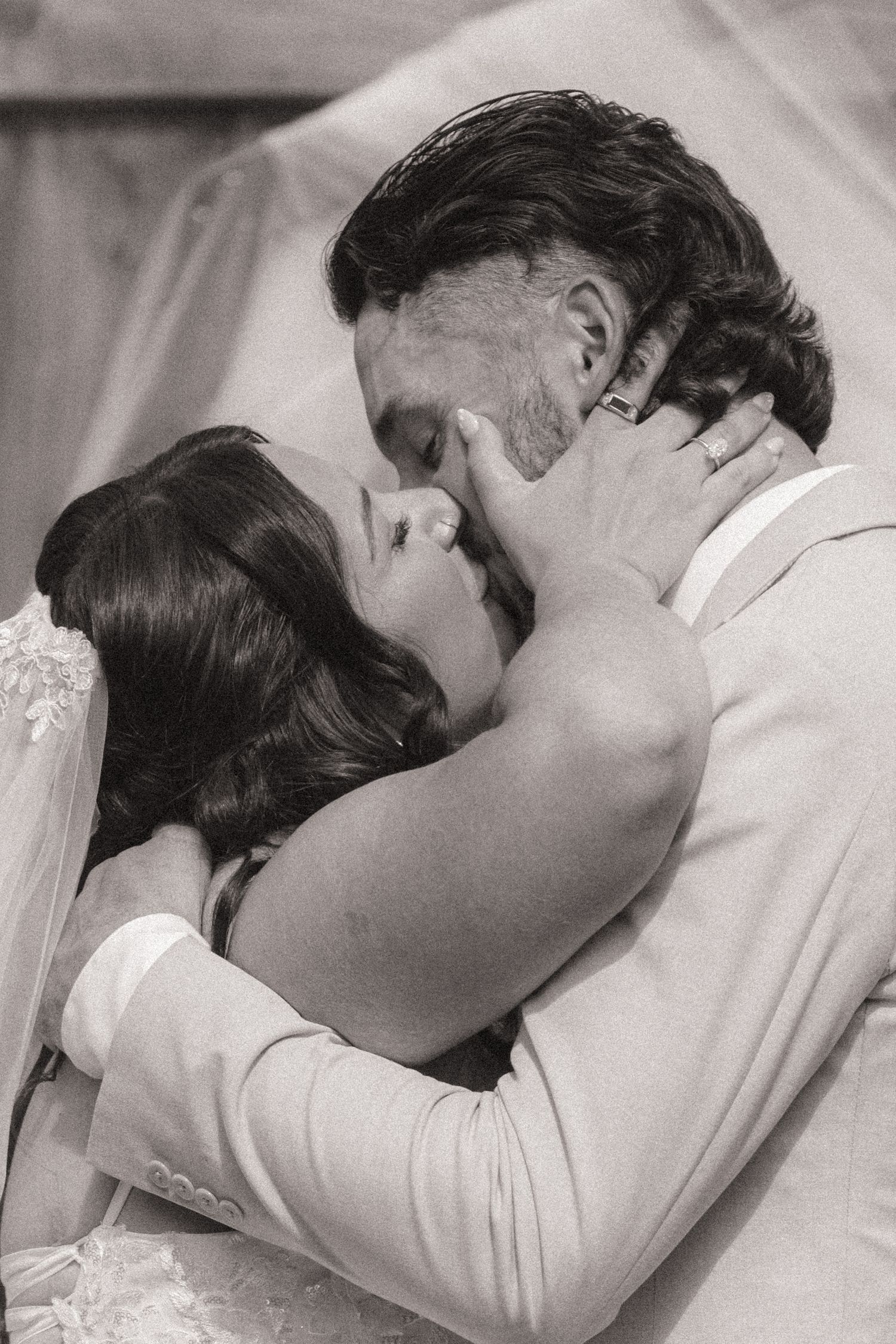 Black and white romantic close-up of bride and groom sharing a passionate kiss on their wedding day.