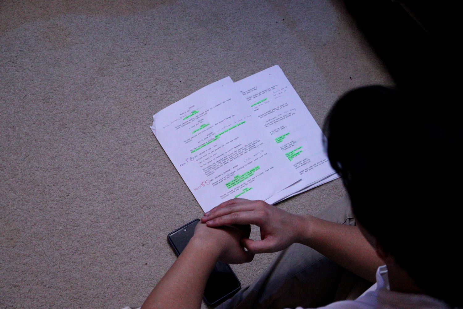 Person reviews highlighted script pages during a film or theater production rehearsal.