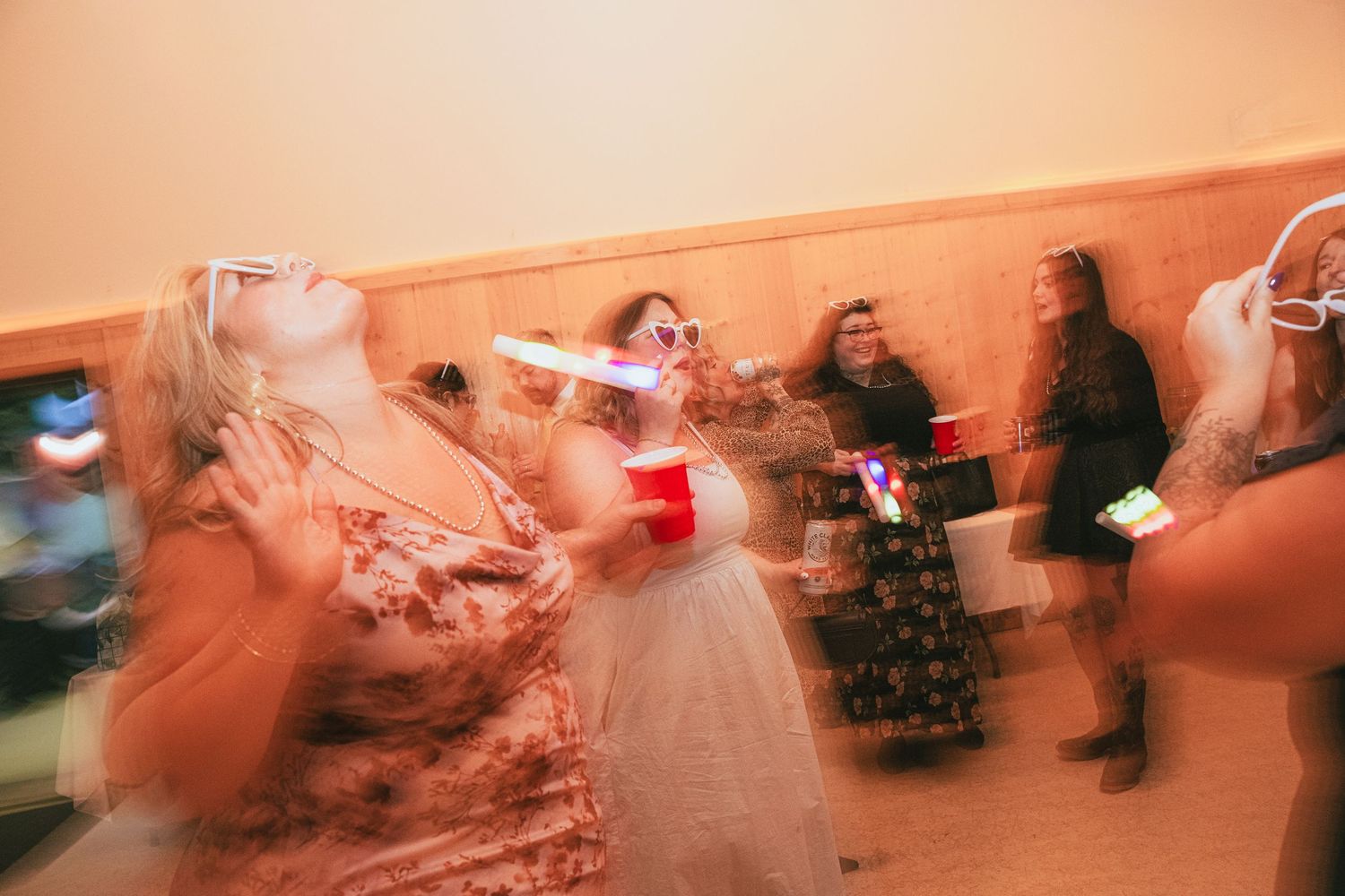 Women dancing at a party, holding red Solo cups, with motion blur capturing the lively celebration atmosphere.