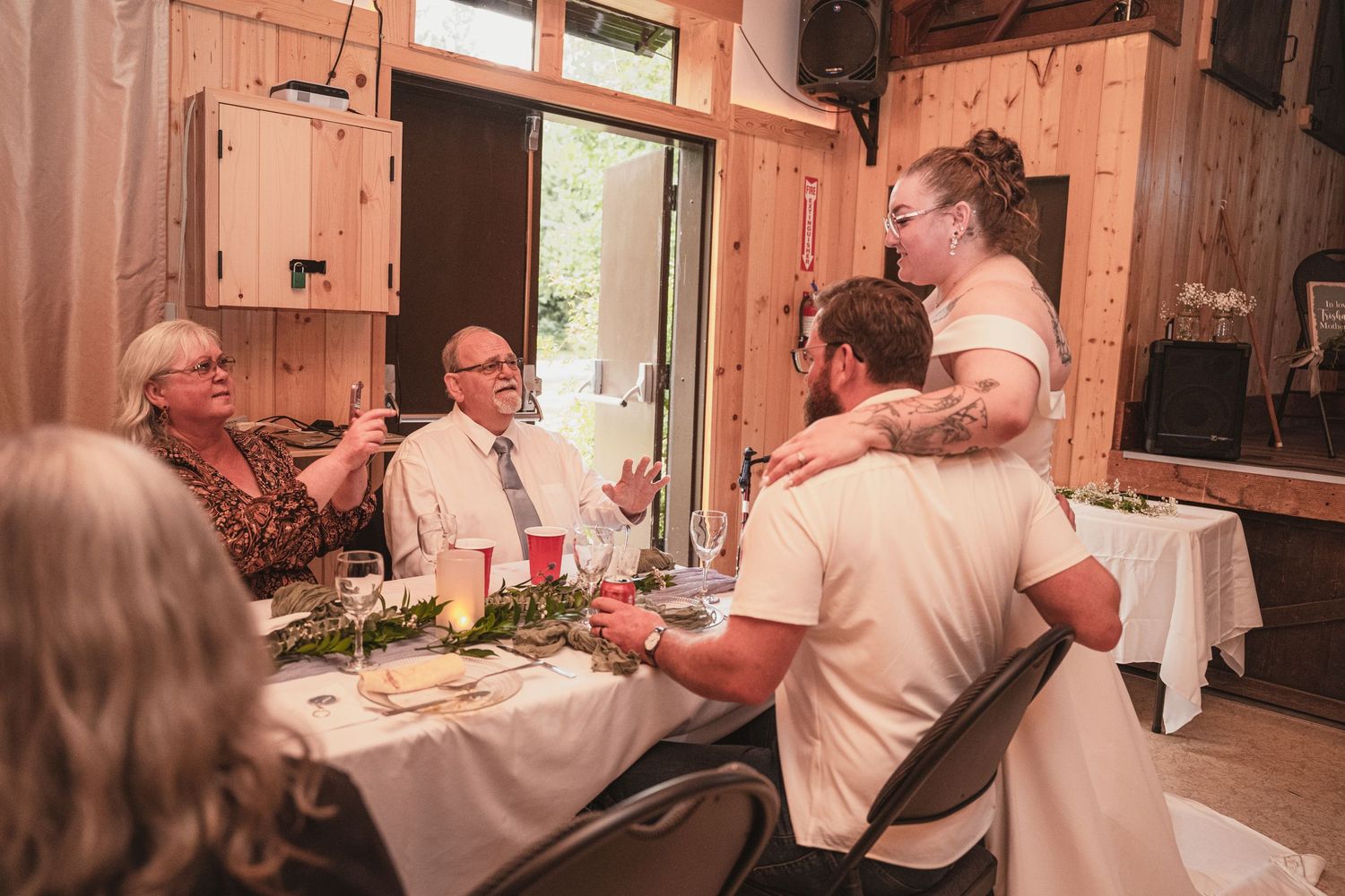 Bride and groom sharing a warm moment with elderly guests at a rustic wedding reception table.