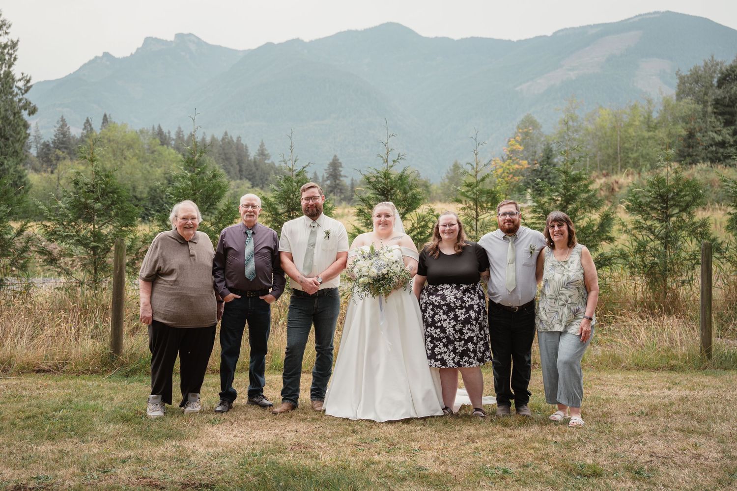 Wedding party of seven people posing together outdoors with scenic mountain backdrop.
