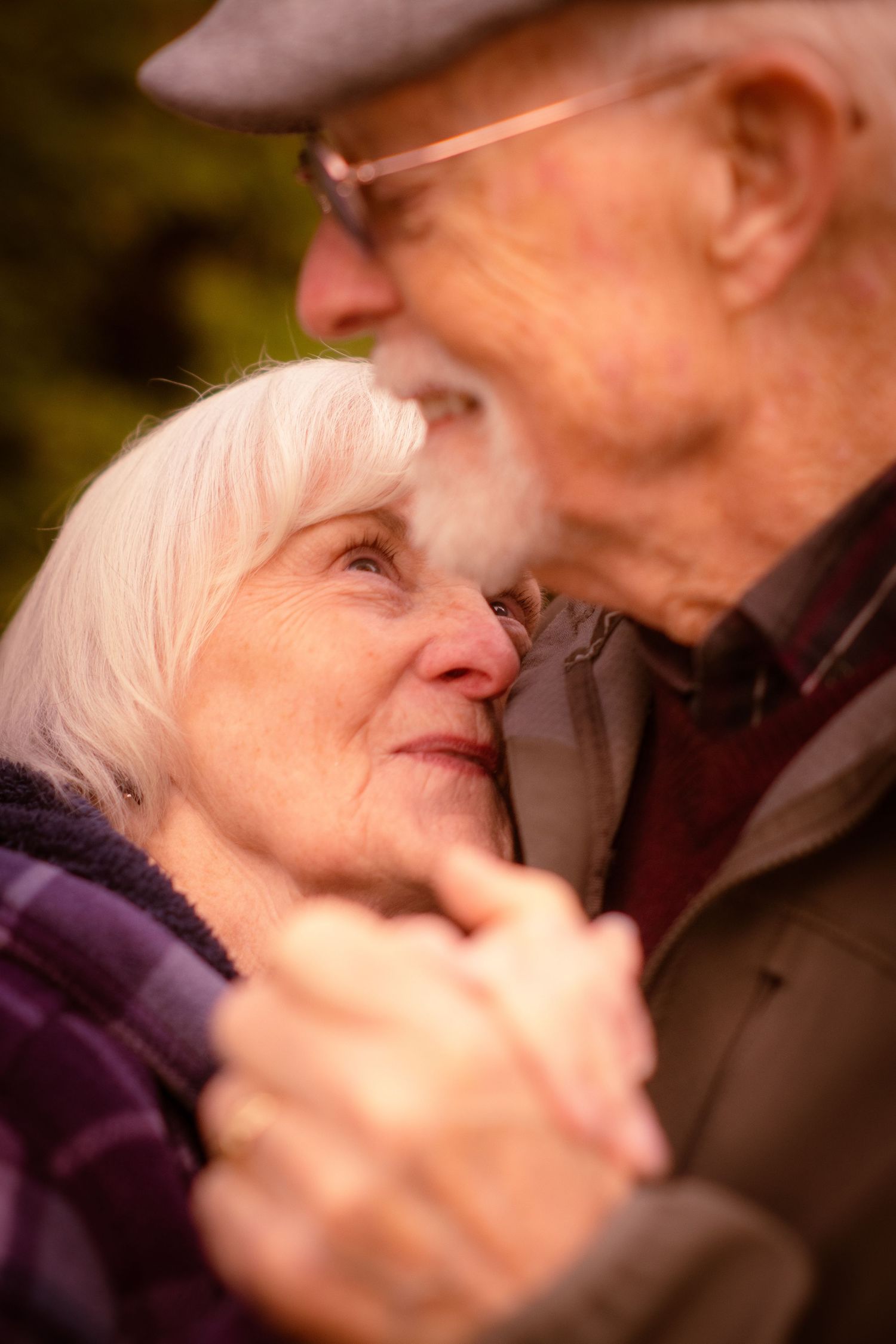 Senior woman gazing up lovingly at man while dancing together outdoors in autumn.