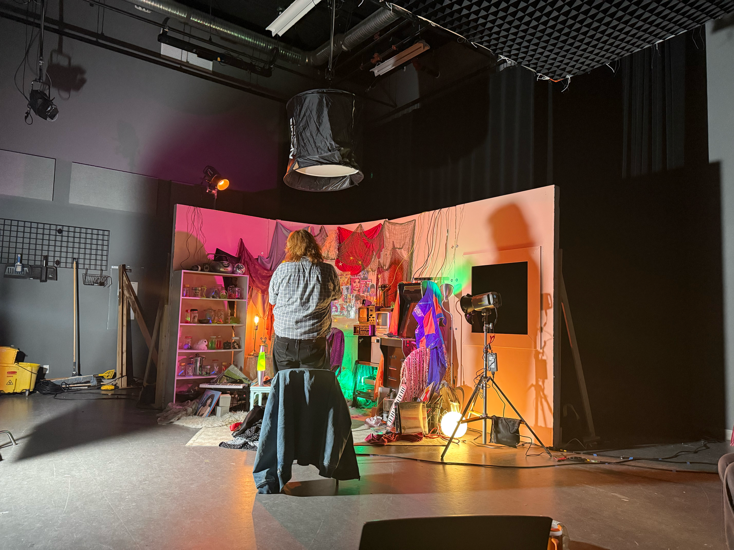 Behind the scenes studio shot showing crew members working on a vibrant neon-lit pop art themed set.