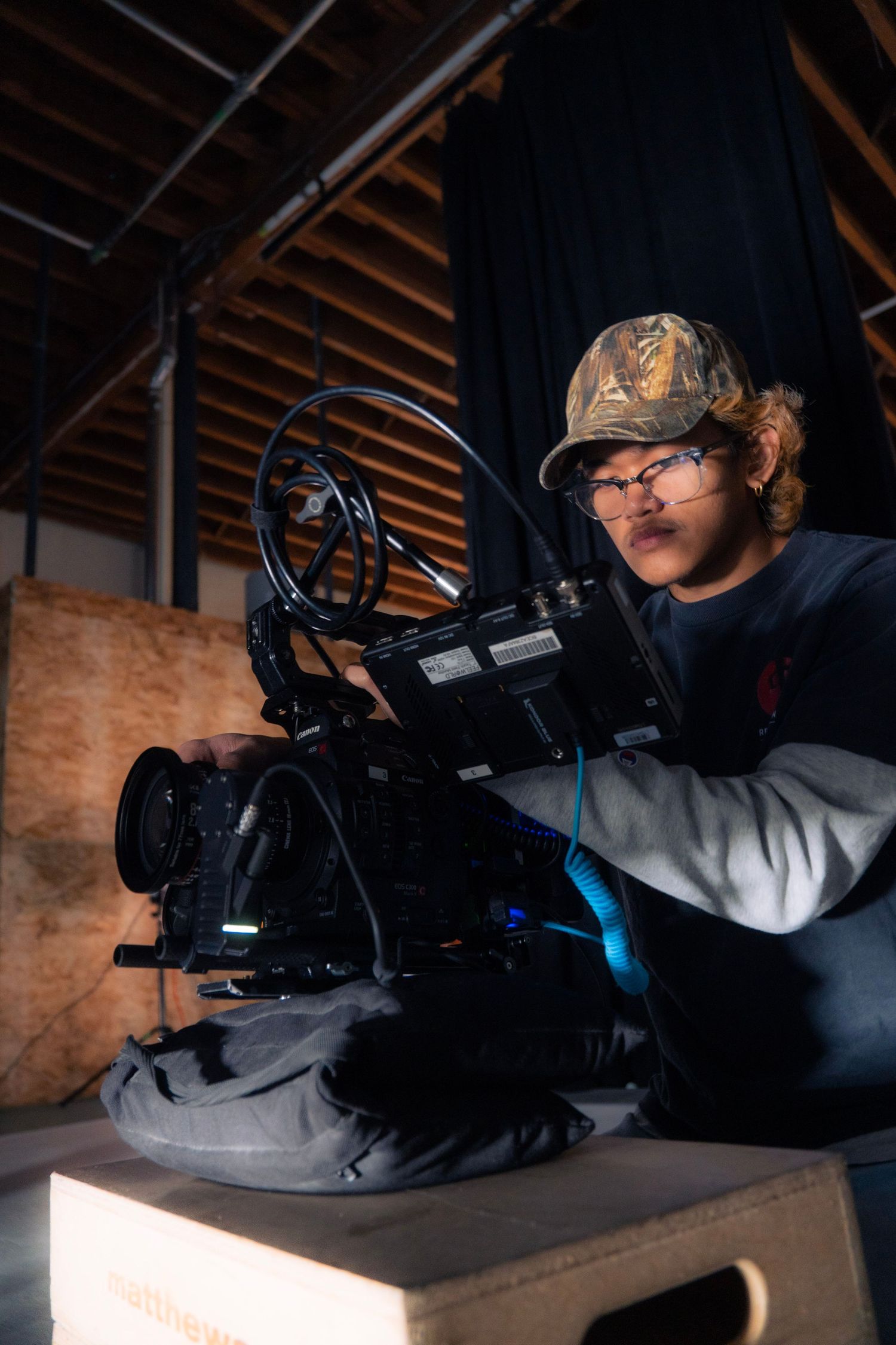 Cinematographer operating a professional film camera on a low angle shot in a dark studio.