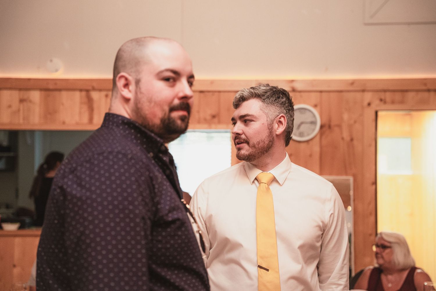 Two men in formal attire share a conversation at a wedding reception venue.
