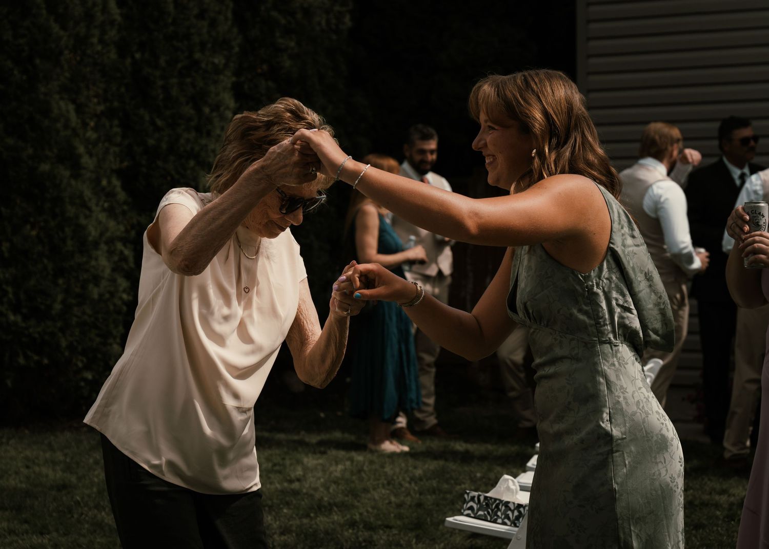 Two women dancing together at an outdoor evening party, one spinning under the other's raised arm.