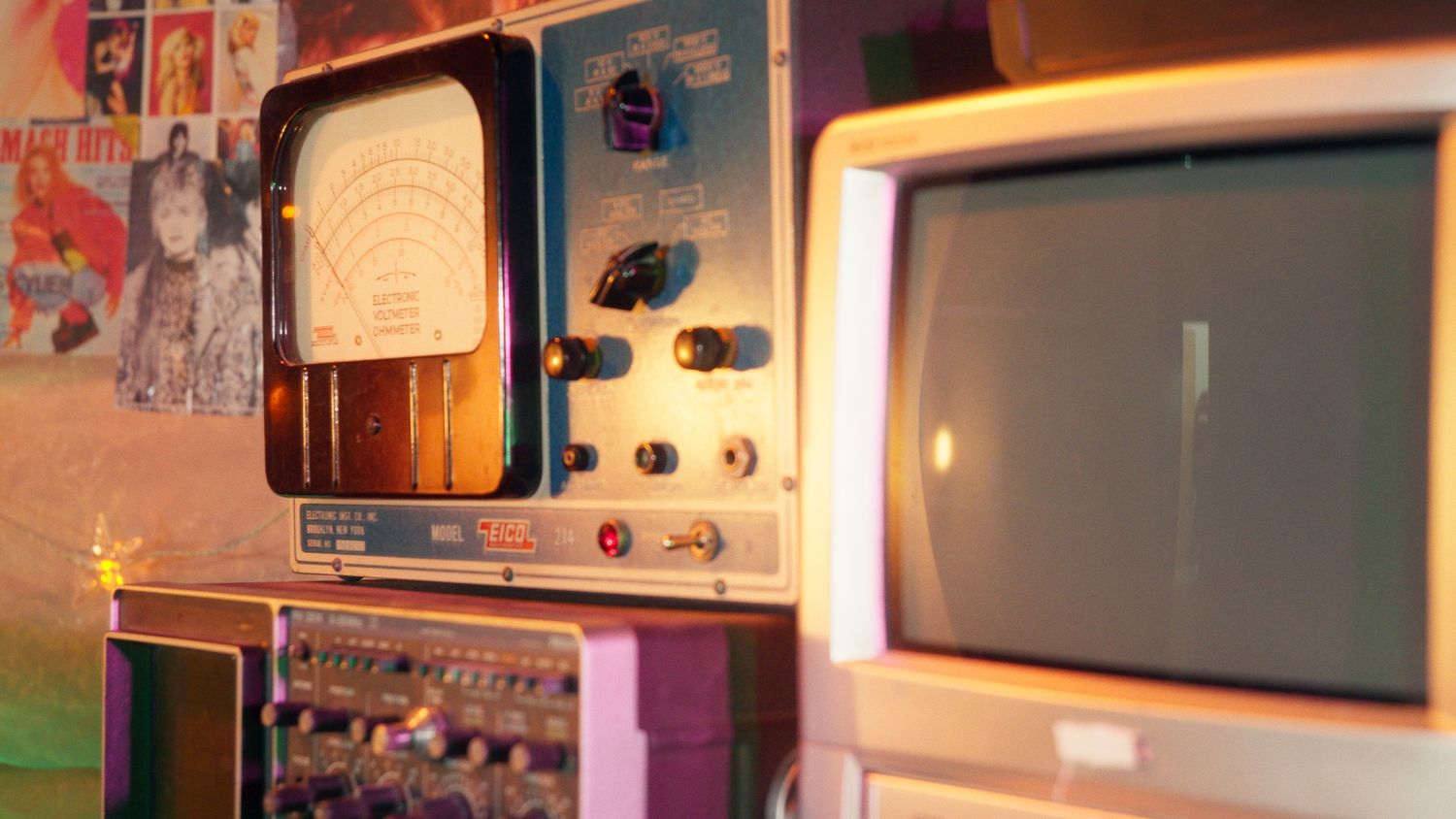 Vintage analog equipment and retro computer monitor with colorful wall decor.