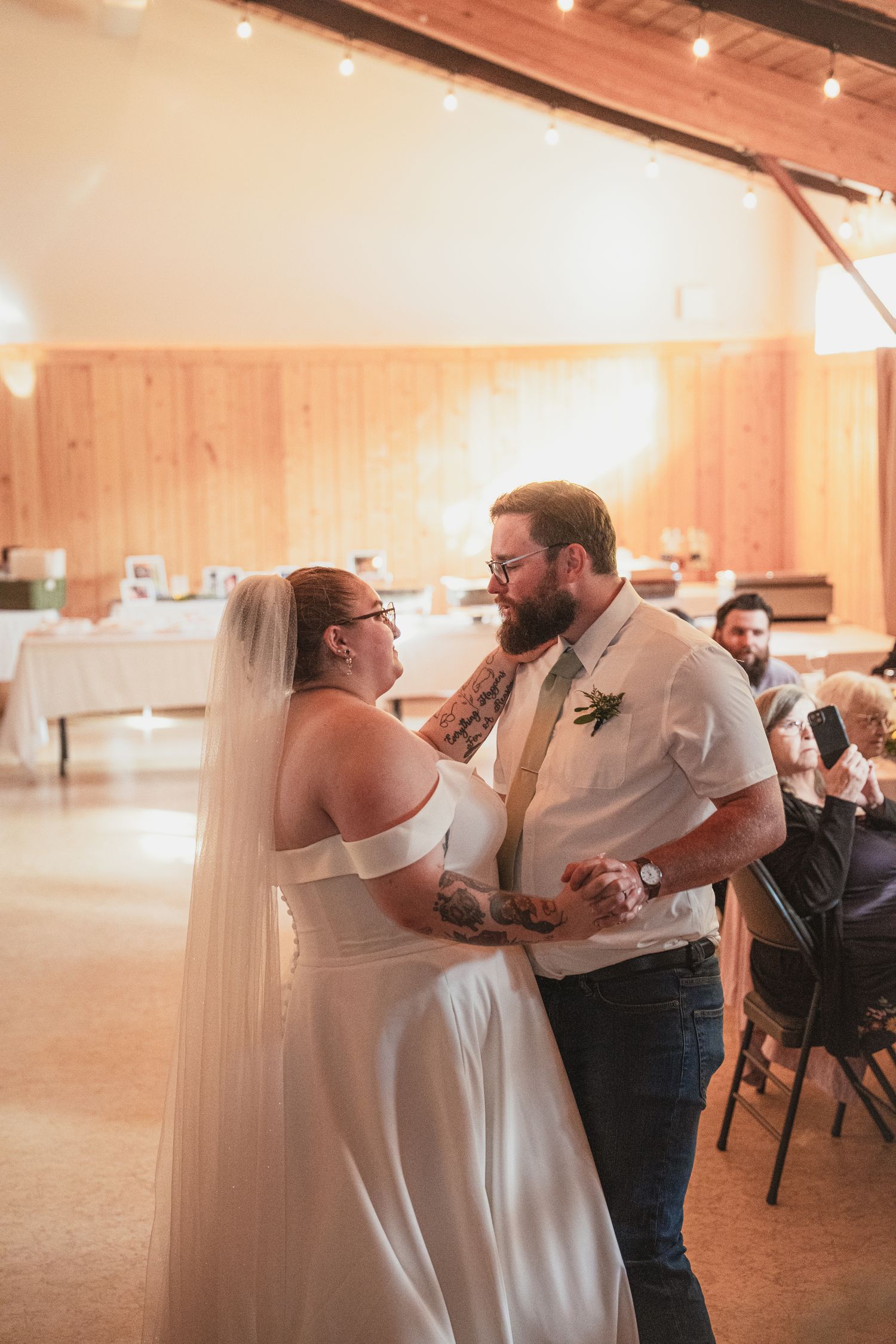 Bride and groom sharing their first dance in a warmly lit rustic barn wedding reception venue.
