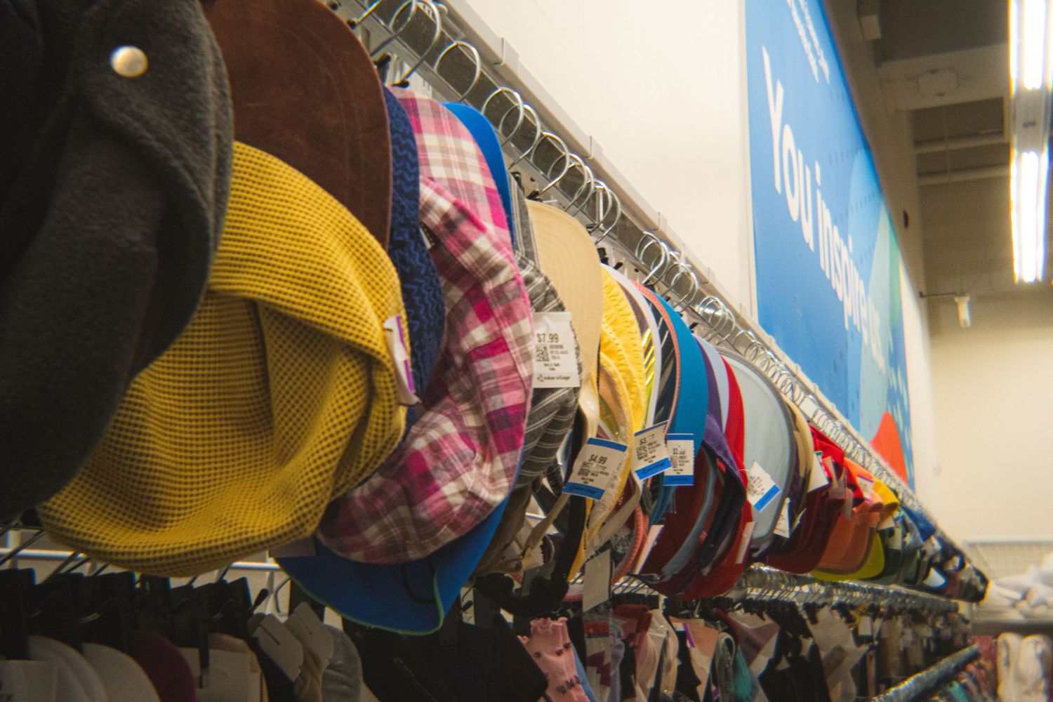 Colorful assortment of hats displayed on a rack in a thrift store.