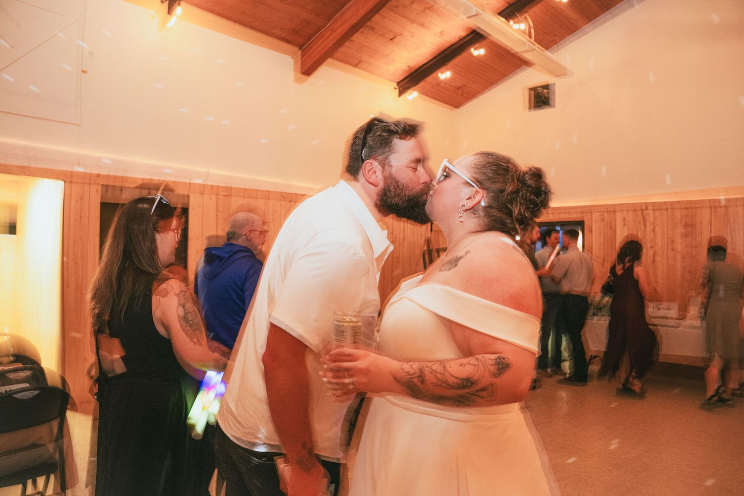 Bride and groom sharing romantic kiss on wedding reception dance floor.