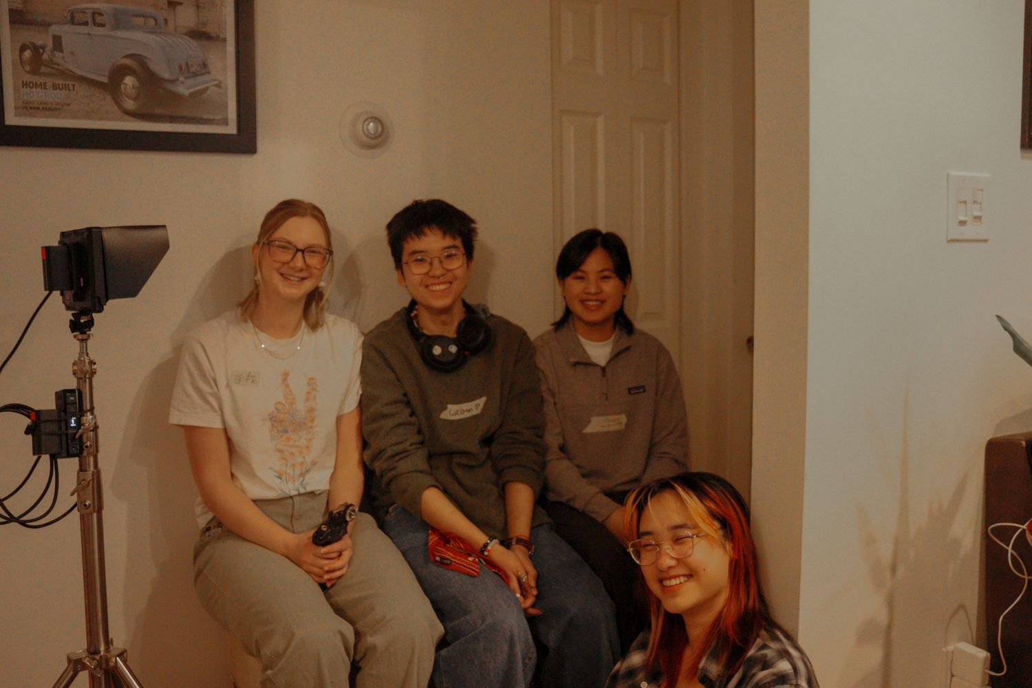 Four young film students smile together on set during a production shoot indoors.