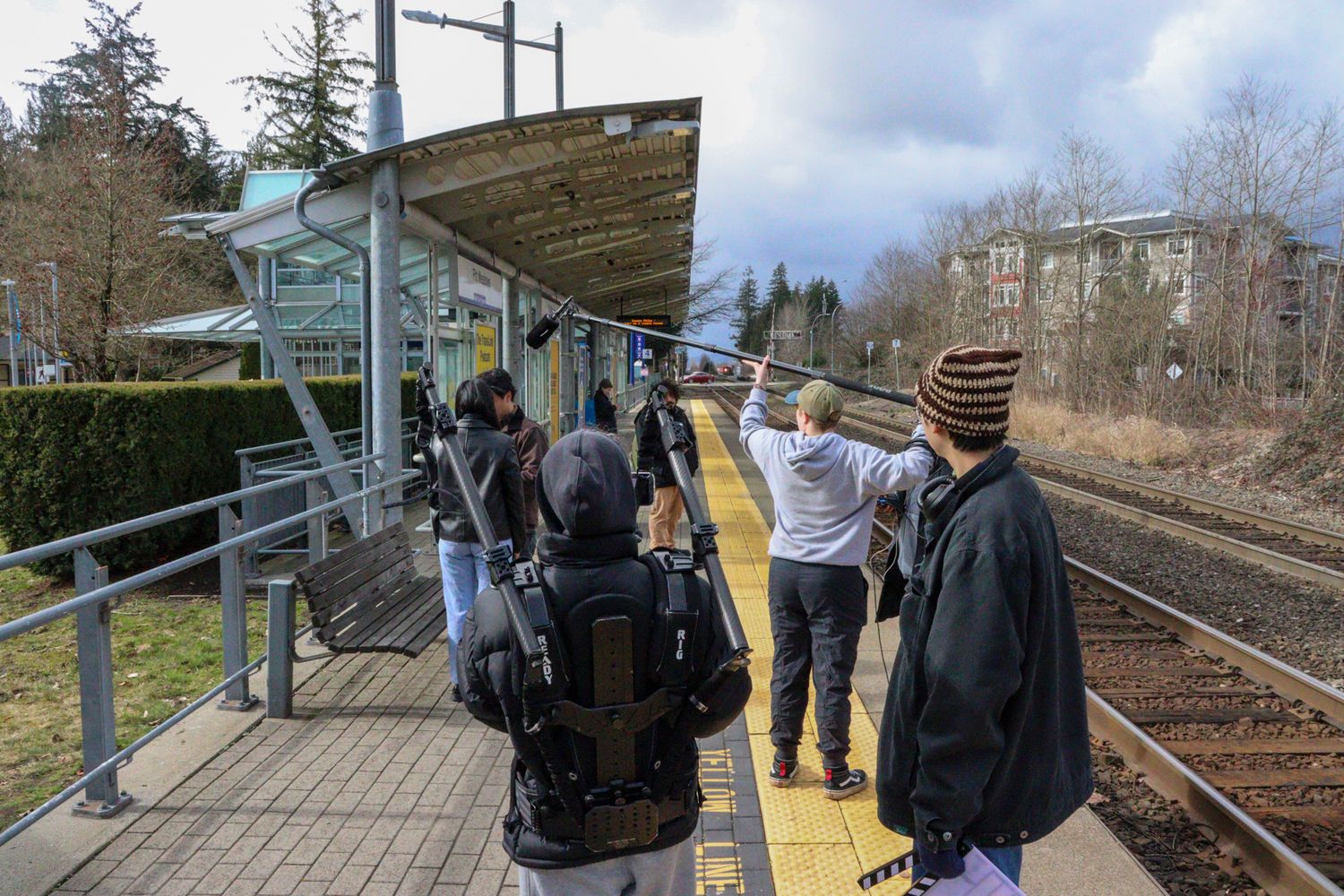 Film crew on a train platform preparing to shoot a scene near the tracks.