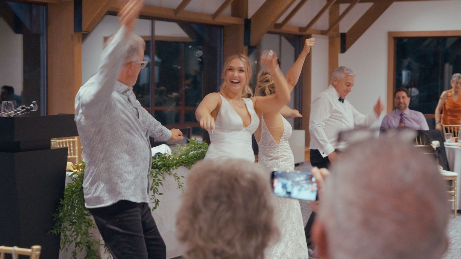 Bride dancing joyfully with guests at wedding reception celebration.