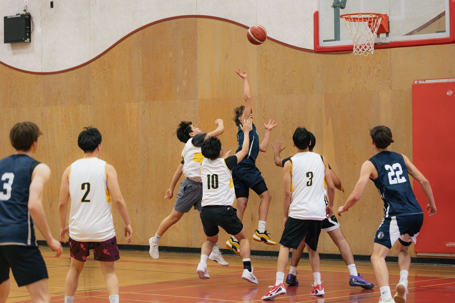Youth basketball players compete during an indoor game with players in navy and white uniforms.