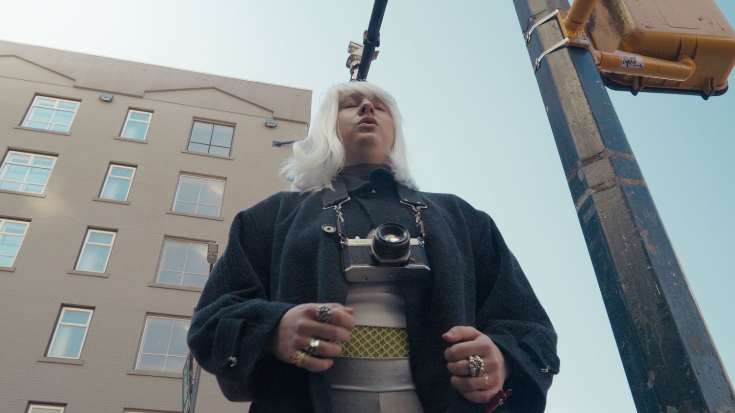 Low angle view of woman with white hair and camera on city street.
