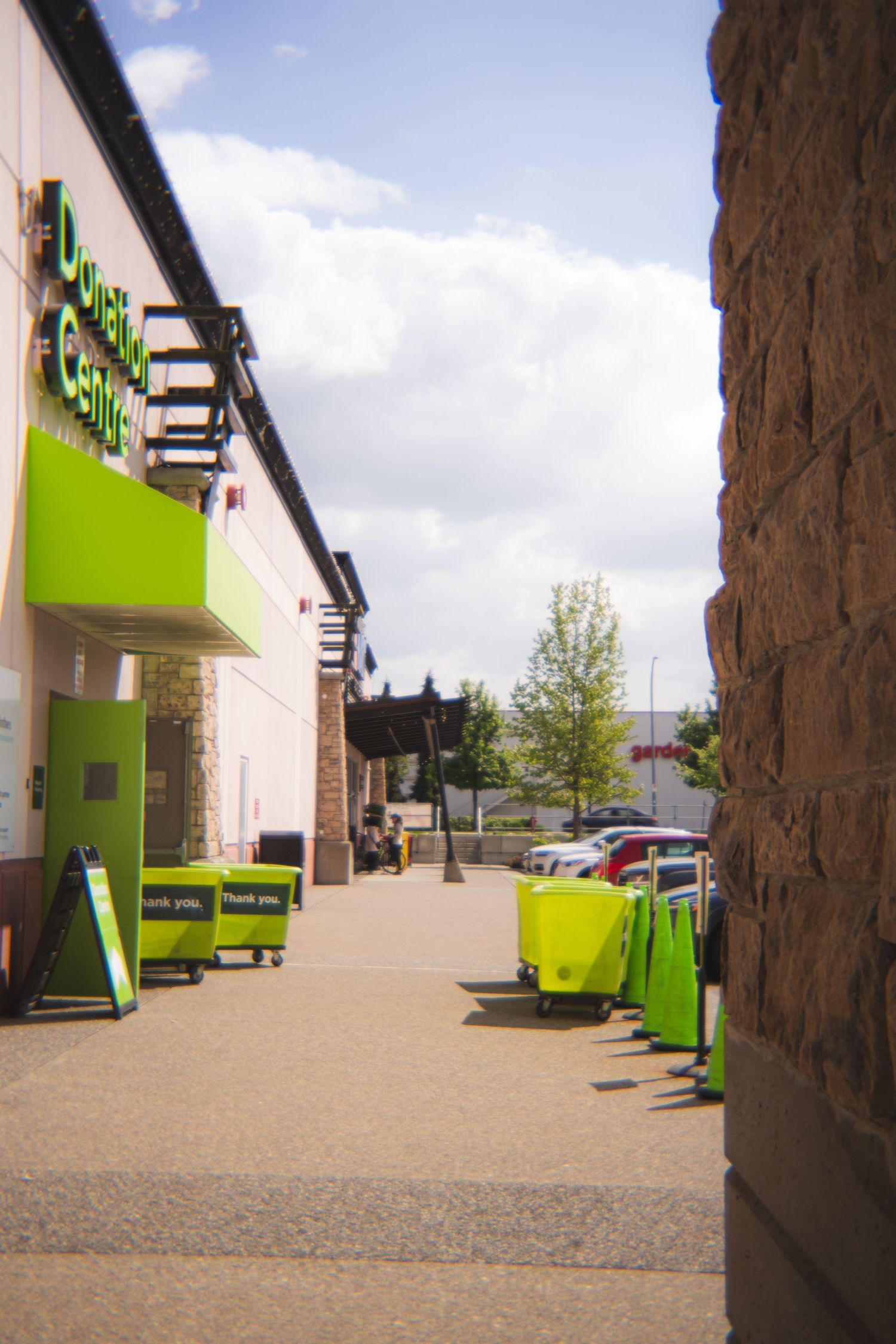 Exterior of a Donation Centre with bright green bins and signage on a sunny day.