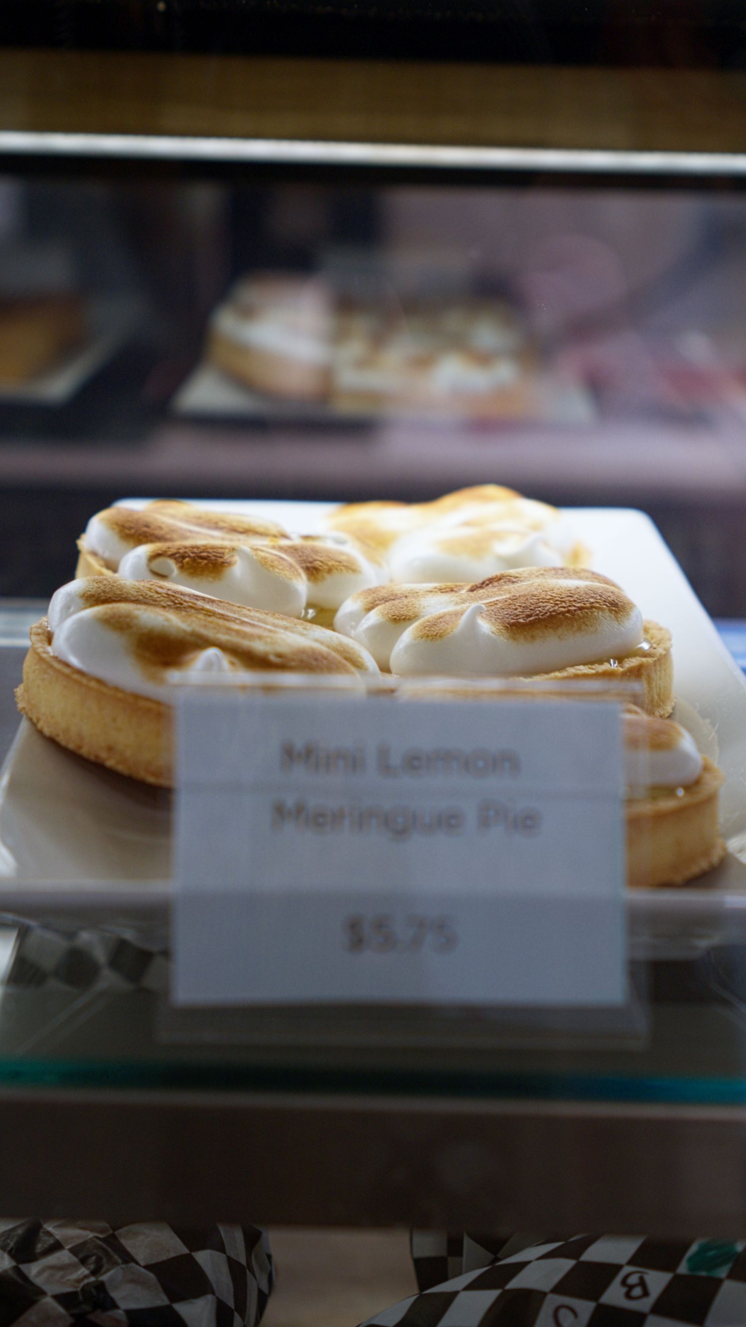 Mini lemon meringue pie with toasted golden meringue topping priced at $5.75 in bakery display case.