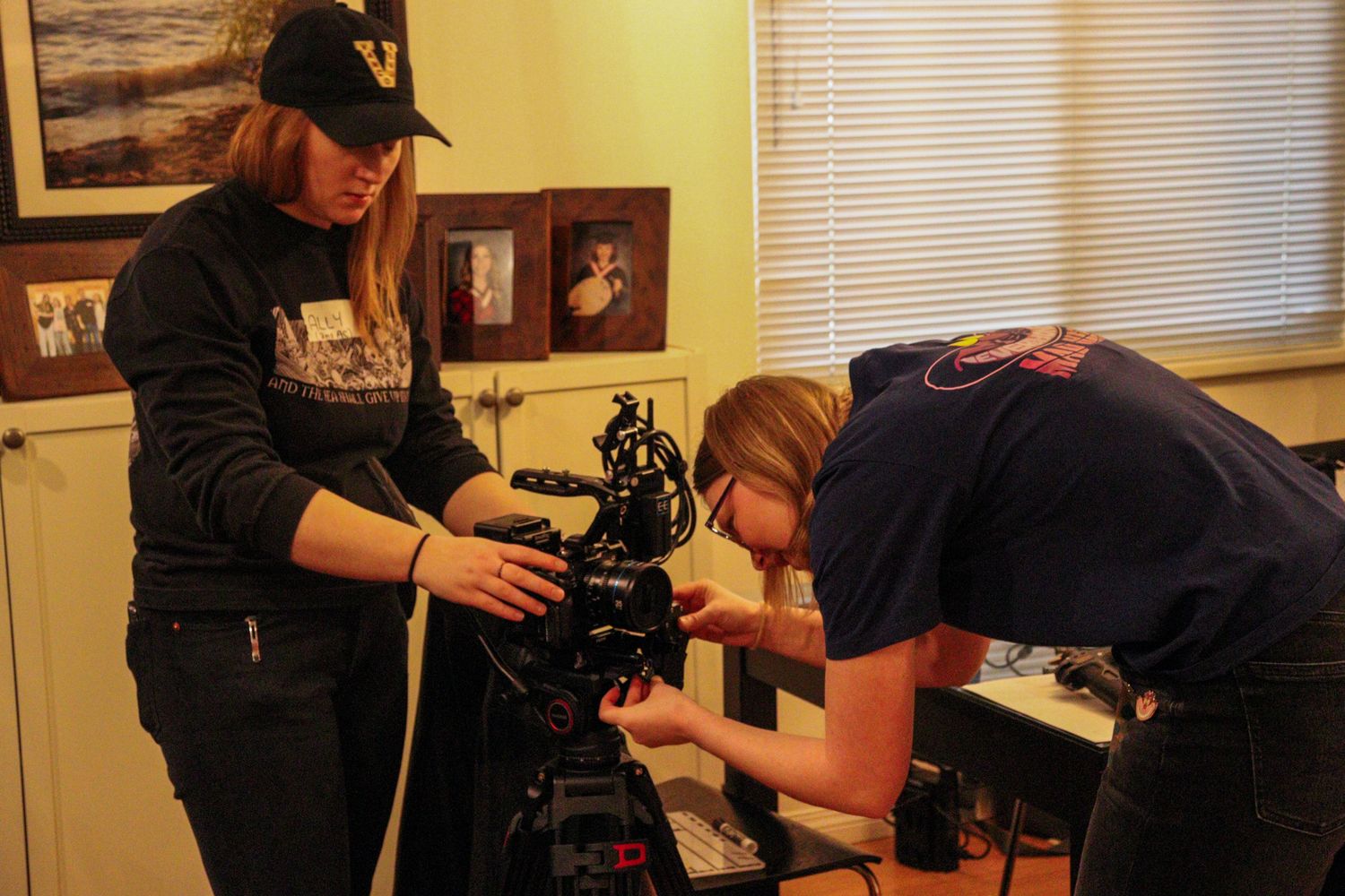 Two women setting up a professional cinema camera on a film set indoors.